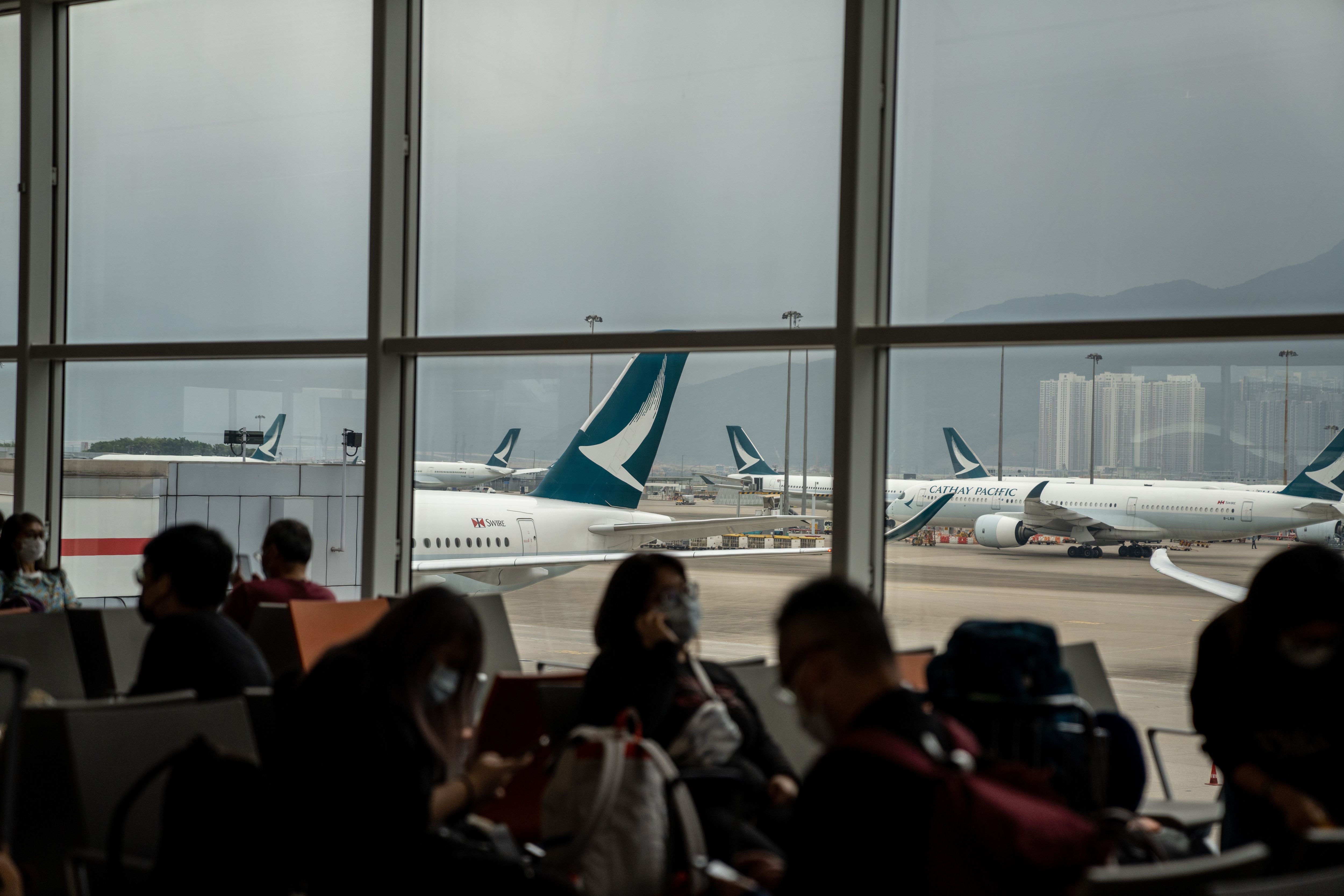 Passengers waiting in Hong Kong. Cathay Pacific planes can be seen in the back. 
