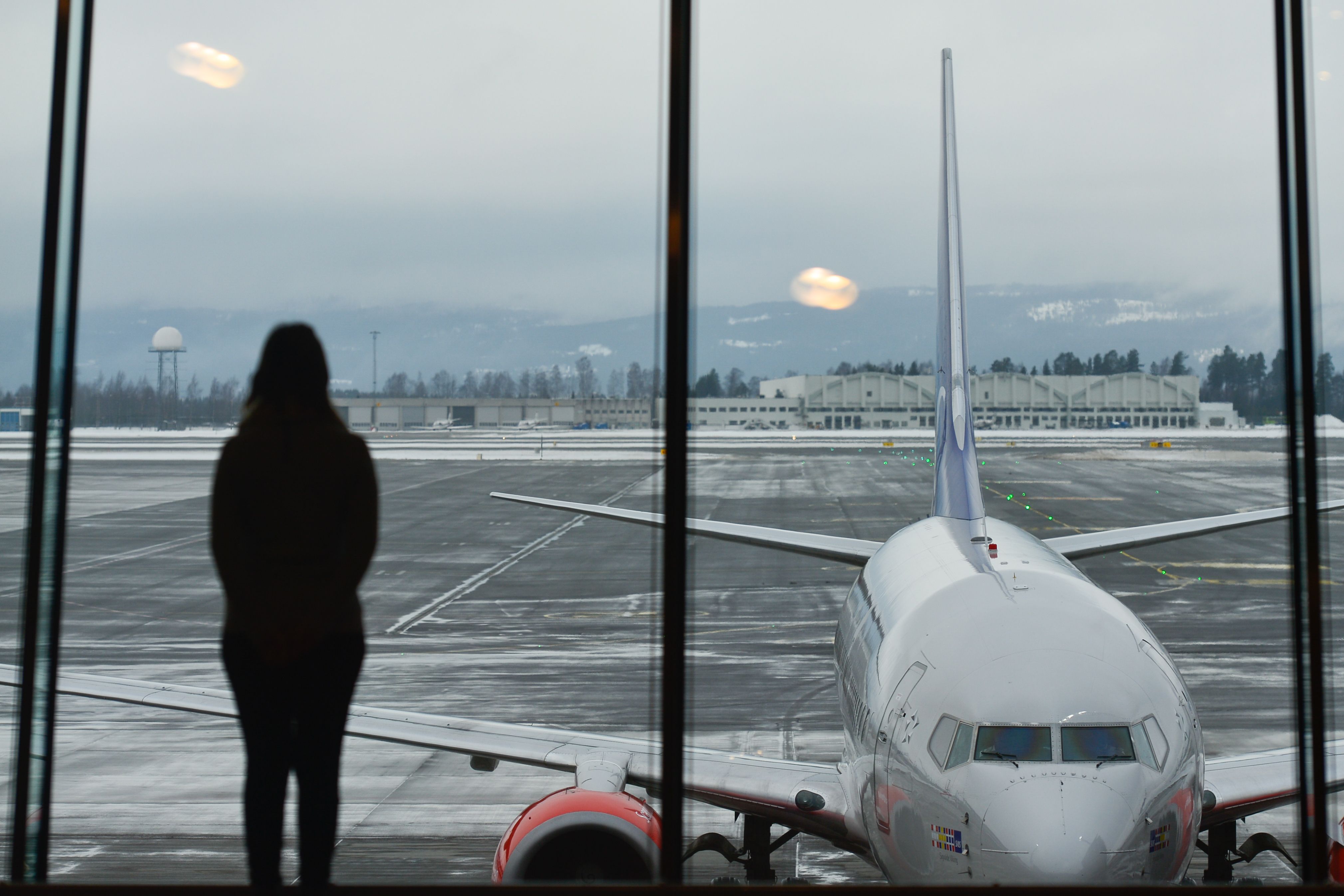 Person looking at aircraft parked at gate Oslo Airport 