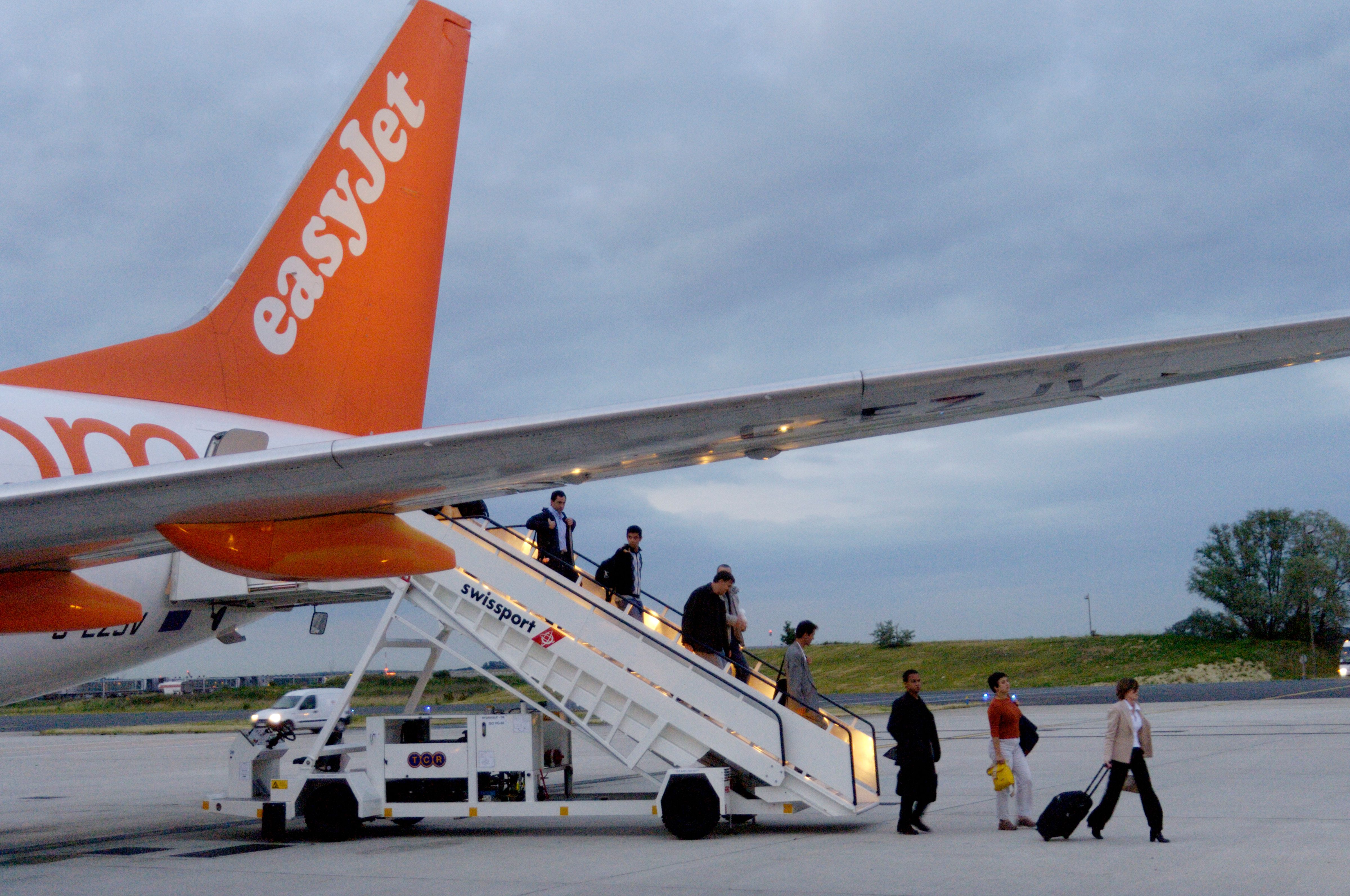 Passengers disembark from an easyJet via staircase from the aircraft's rear door