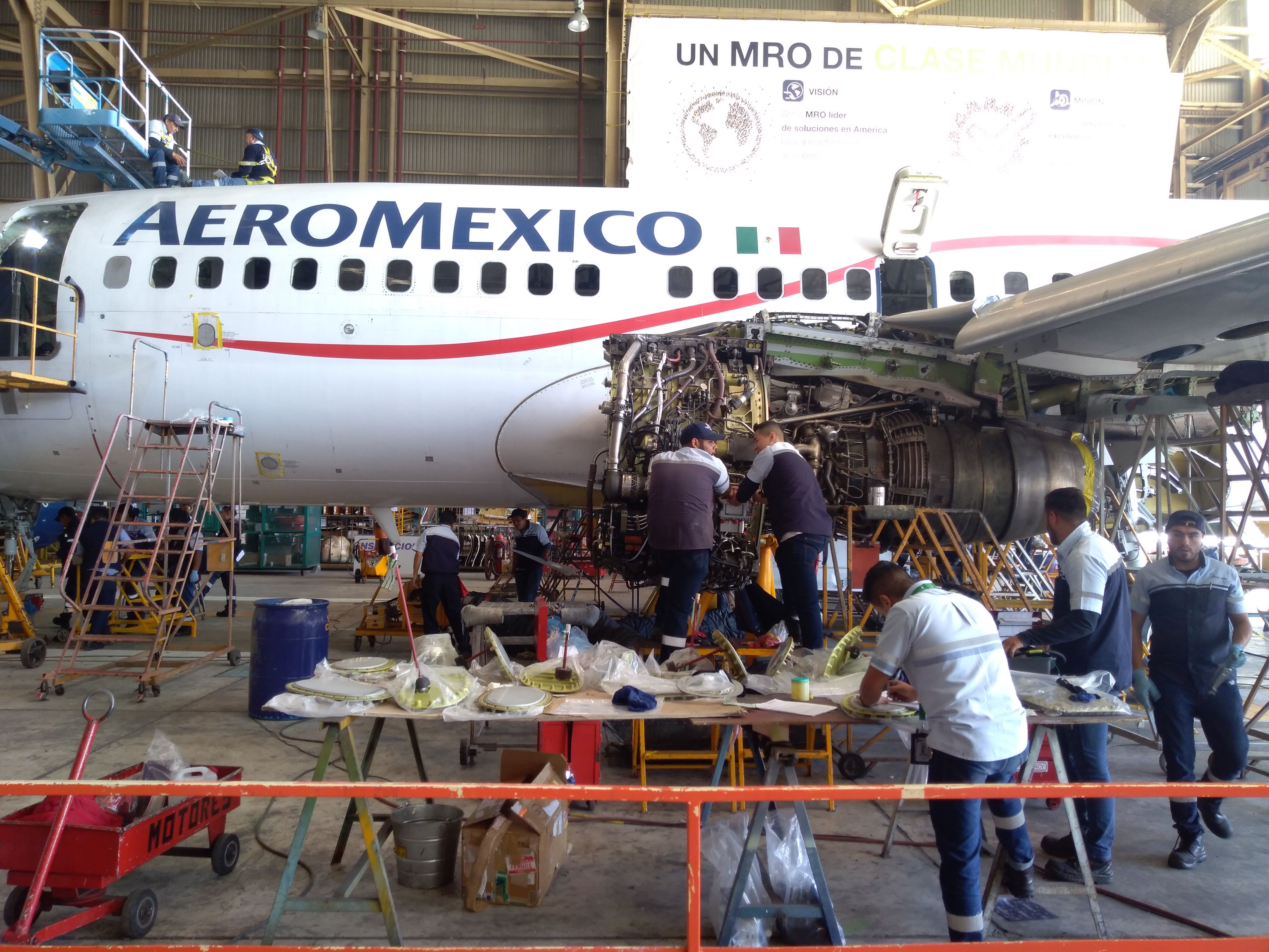 Aircraft mechanics working on the left engine of an Aeromexico Boeing 737 aircraft. 