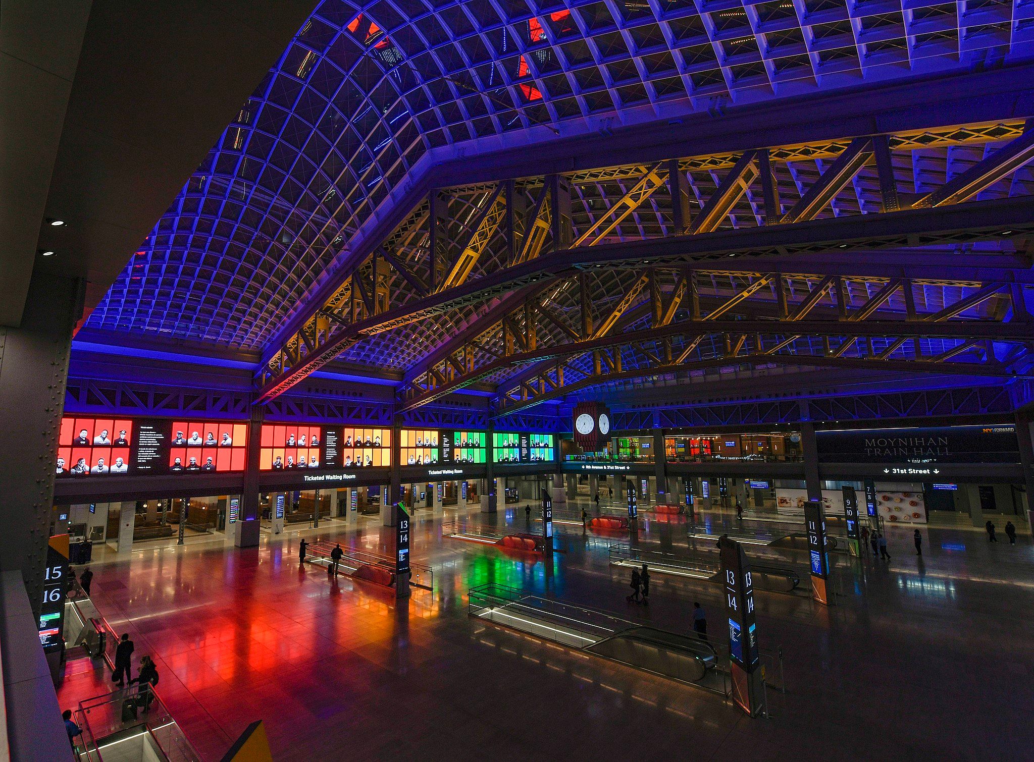 Interior of Penn Station lit in rainbow colors at night