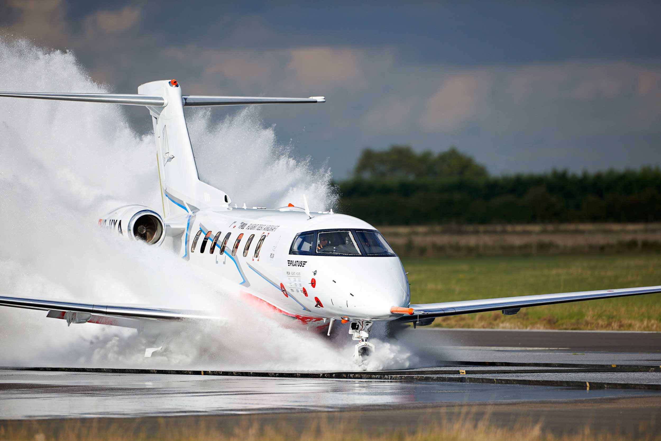 A Pilatus-PC-24 landing on a runway completely flooded with water.