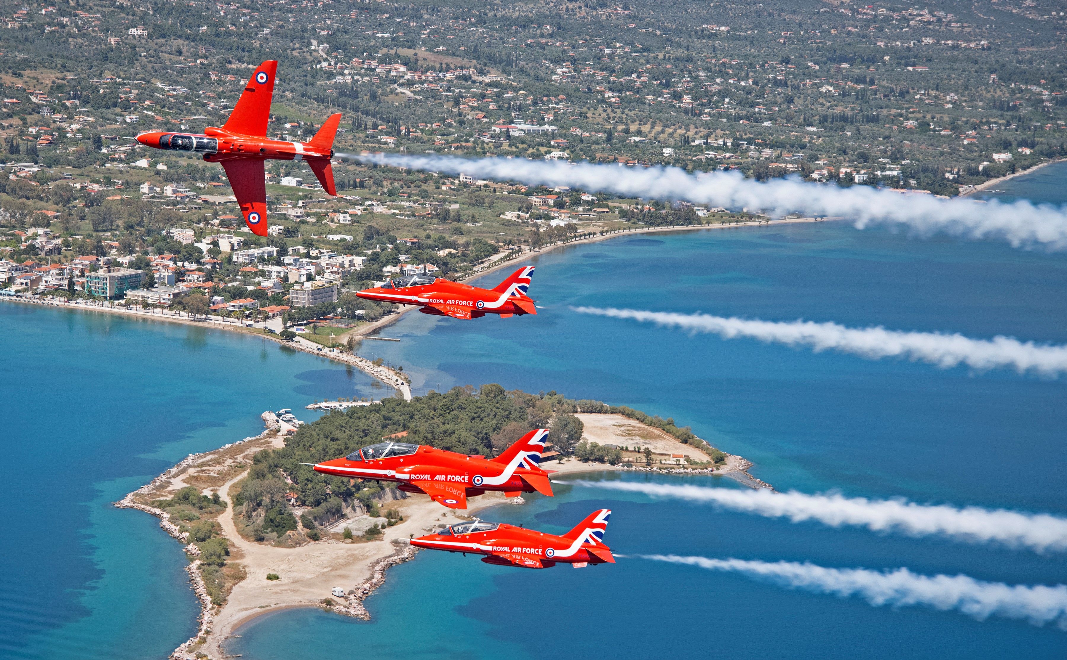 Four bright red fighters fly in formation as part of a performance.