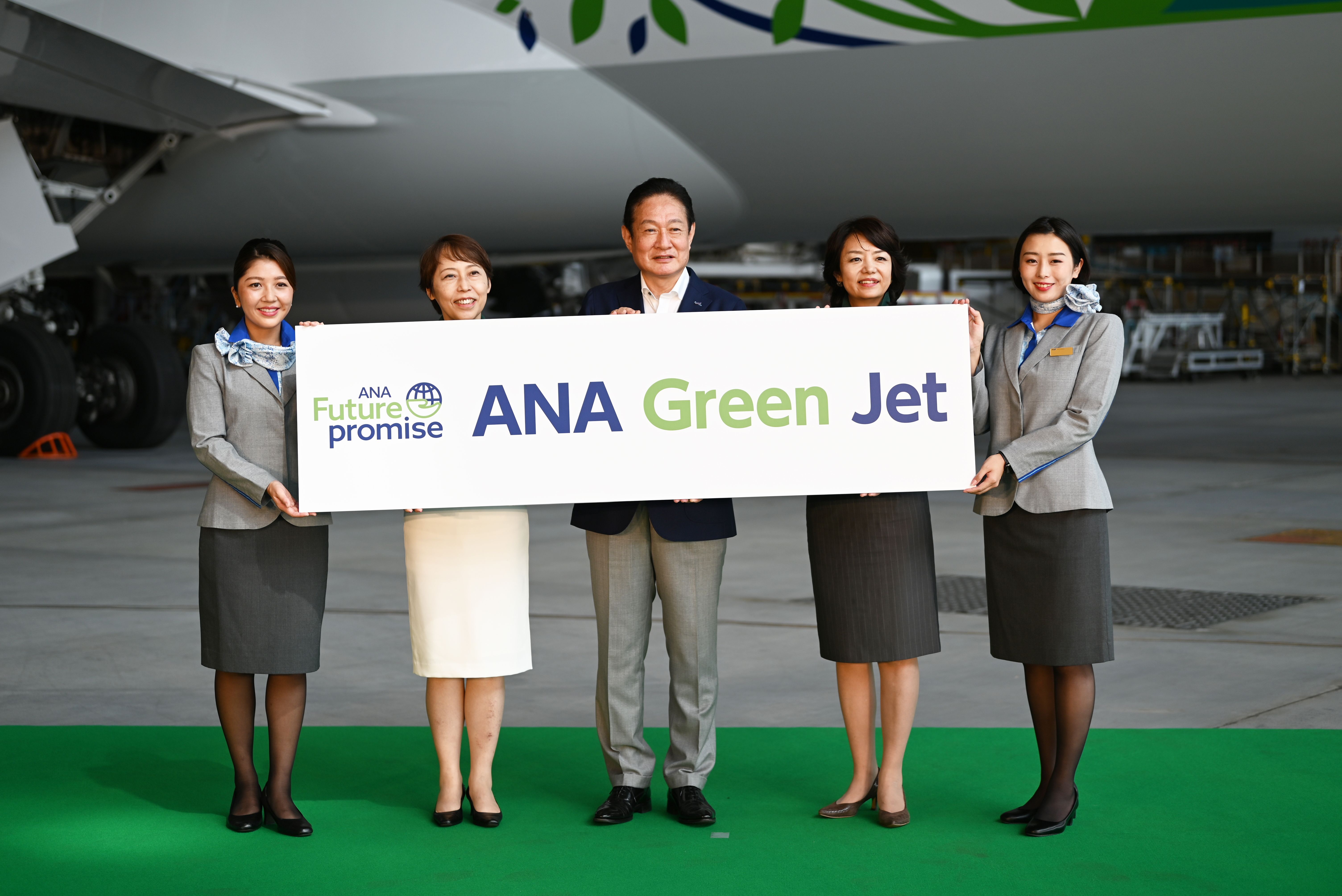 ANA staff members holding a green jet sign