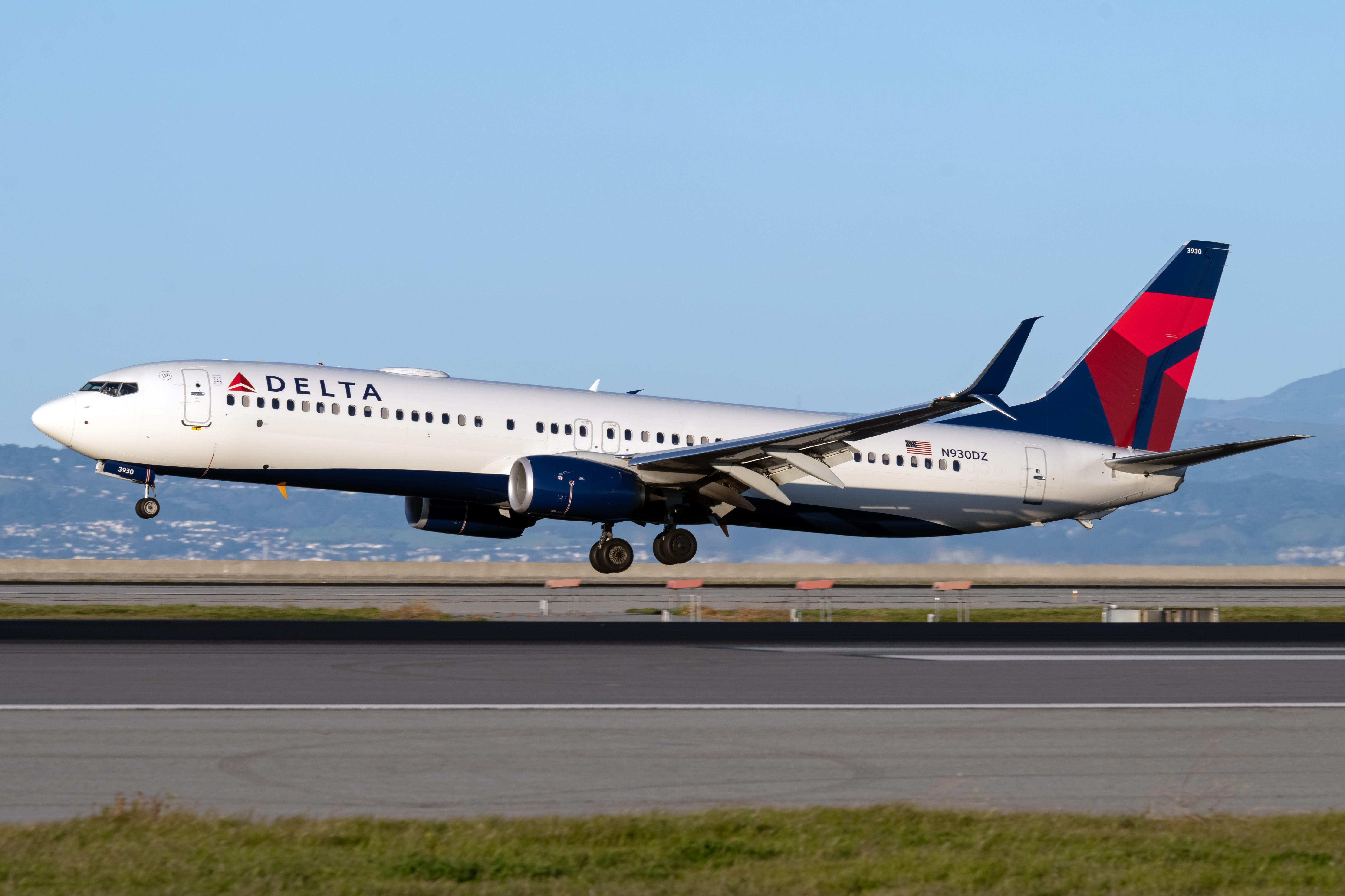 A Delta Air Lines Boeing 737-900 floating just above the runway.