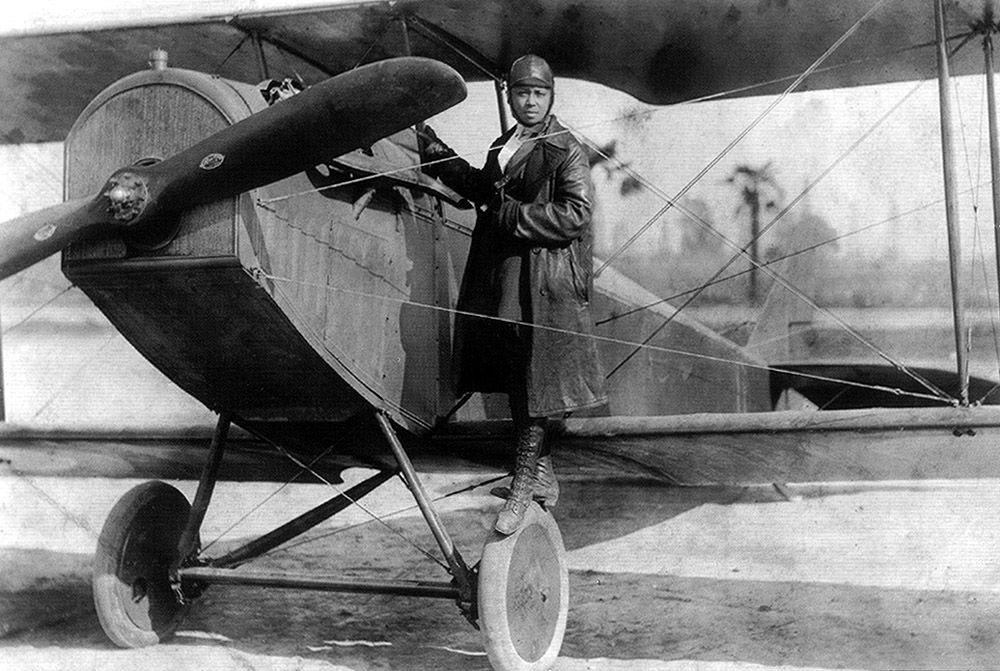 Bessie Coleman standing by her aircraft
