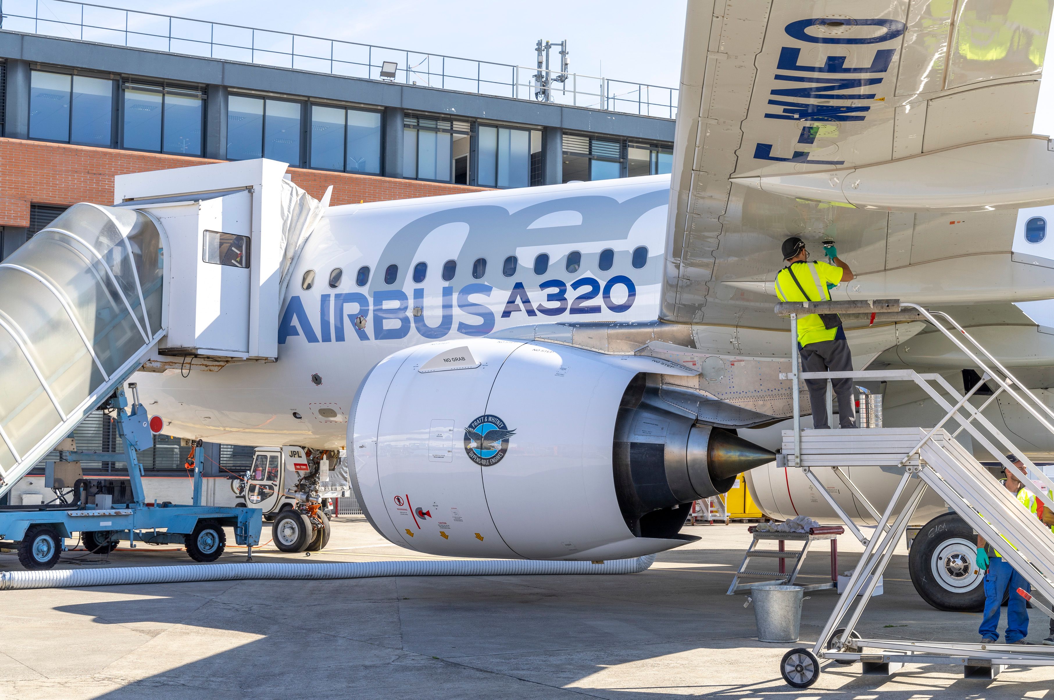 An Airbus A320neo parked at an airport with its engine in full view.