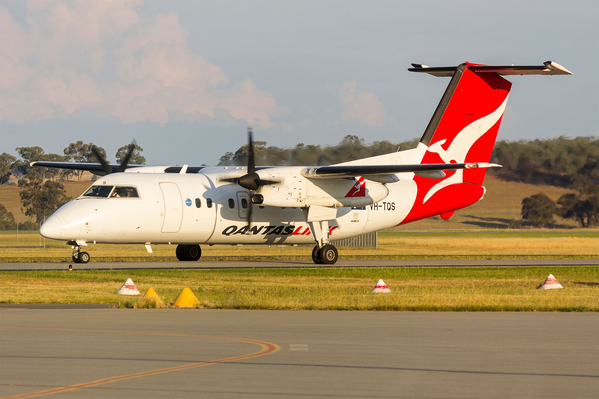 A QantasLink Dash 8 Series 200 aircraft, registration VH-TQS, taxiing to the runway.