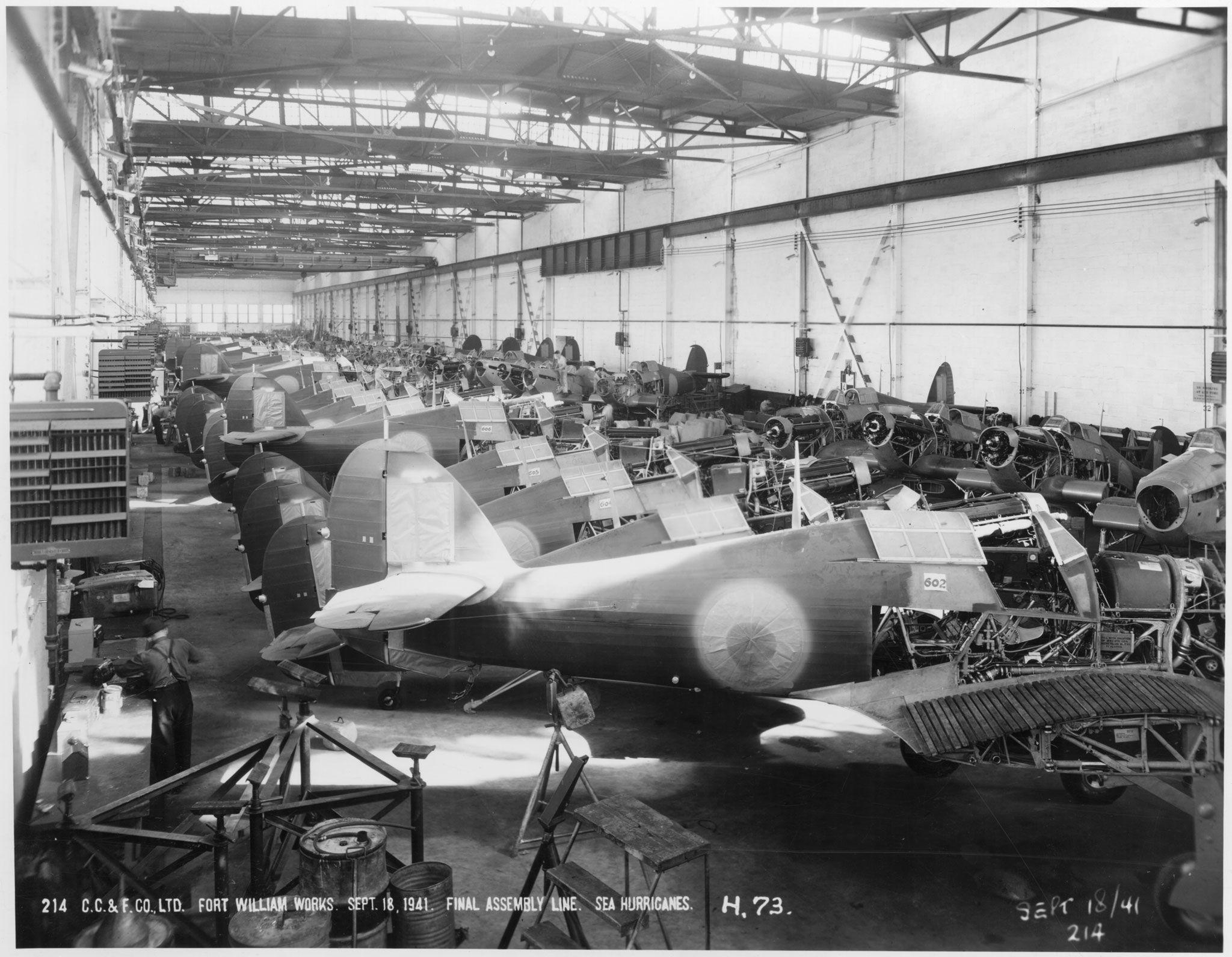 Interior of an assembly plant with a row of fighter planes in the assembly process
