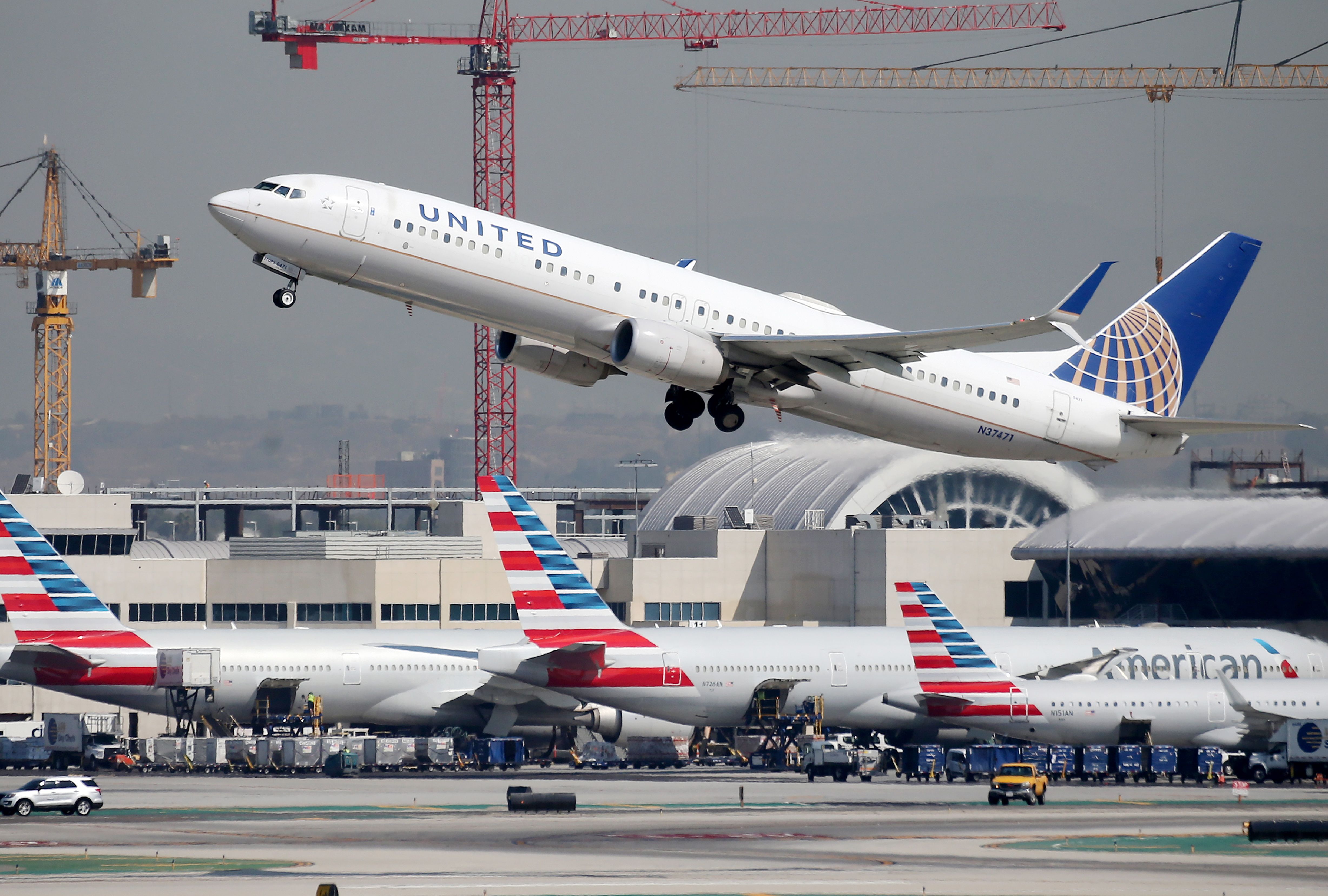 United Airlines Airplane overflies American Airlines Airplanes at Airport 