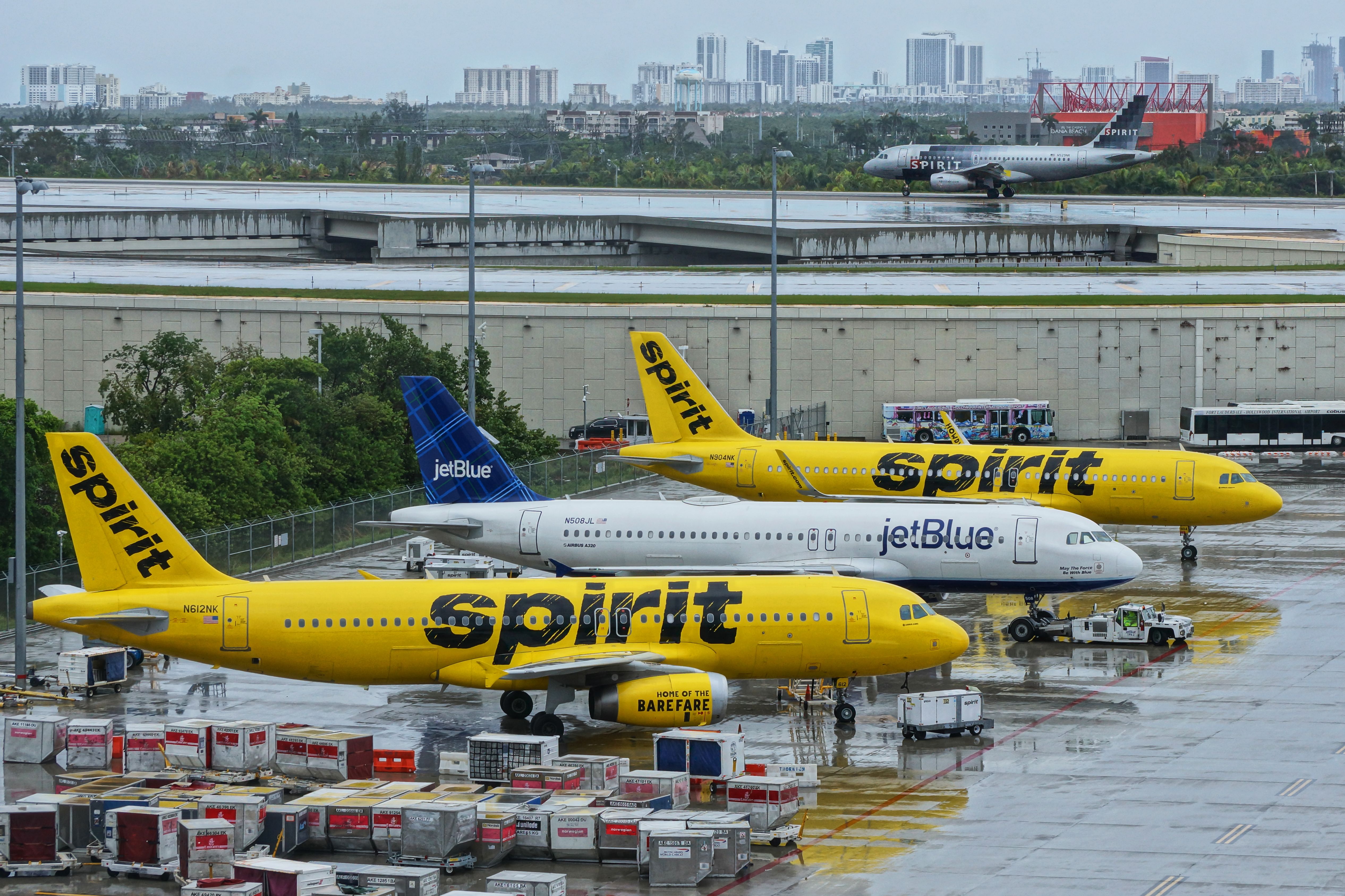 A jetBlue aircraft parked between two Spirit Airilnes aircraft on an airport apron.