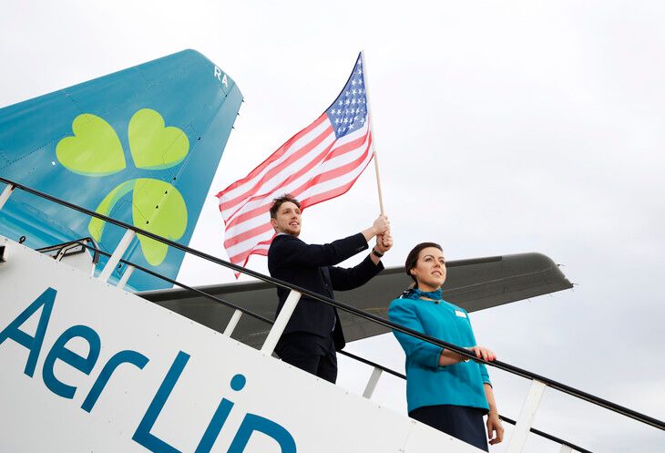 An Aer Lingus crew member holds an American flag while disembarking.