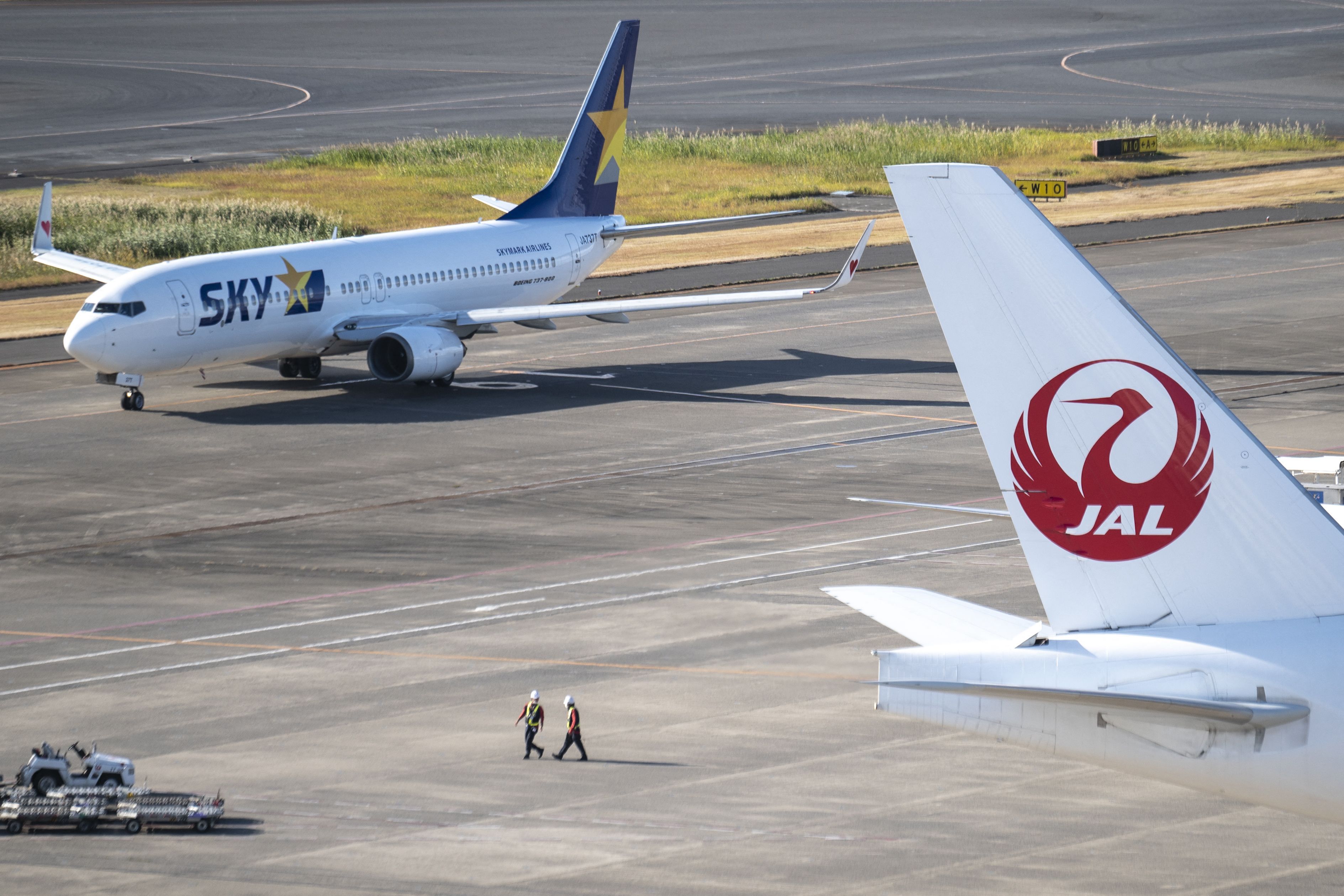 A Skymark Airlines Boeing 737-800 is seen past the tail section of a Japan Airlines (JAL) aircraft at Haneda airport in Tokyo