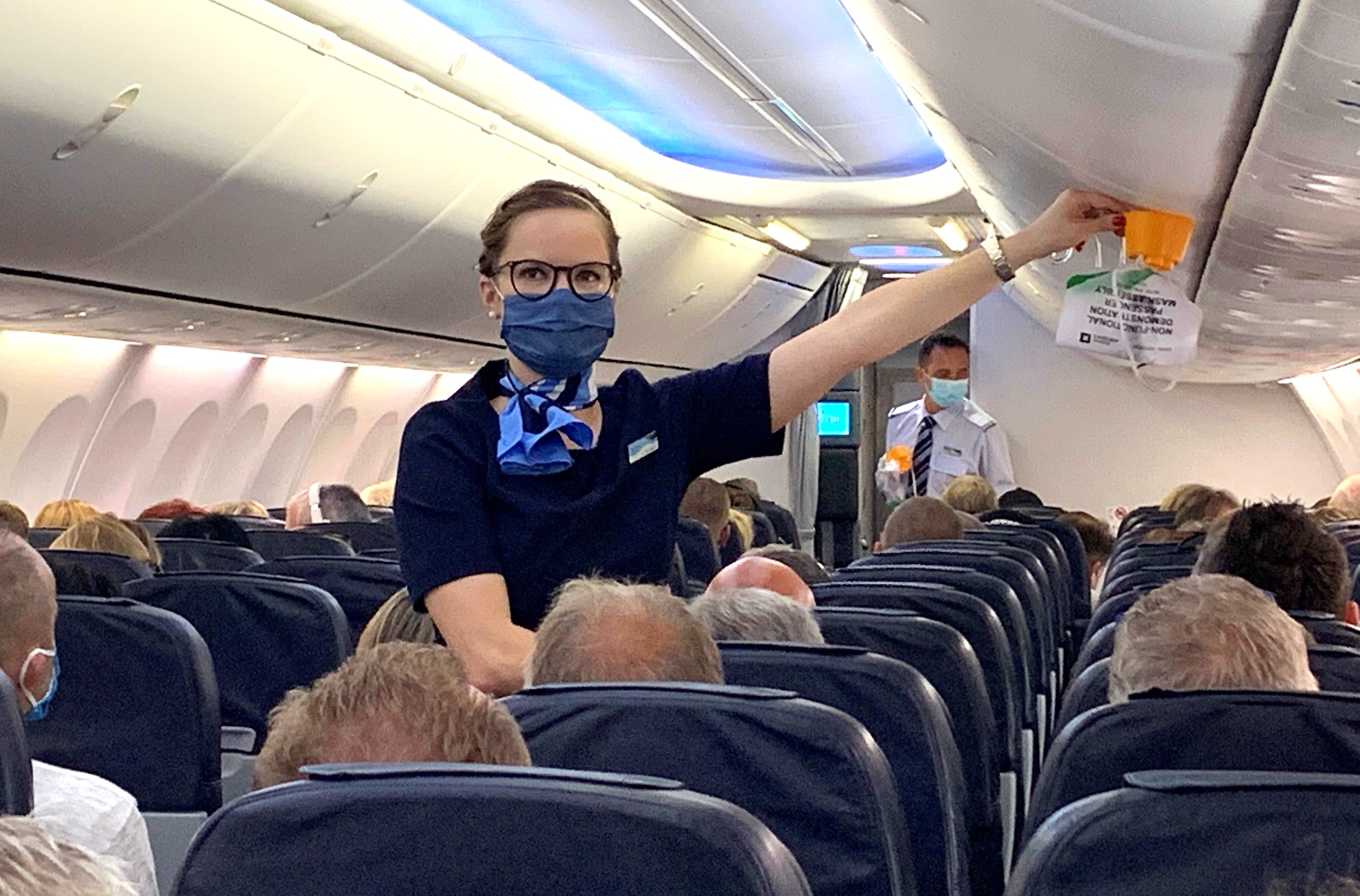 A flight attendant gives safety instructions to tourists prior to the departure 