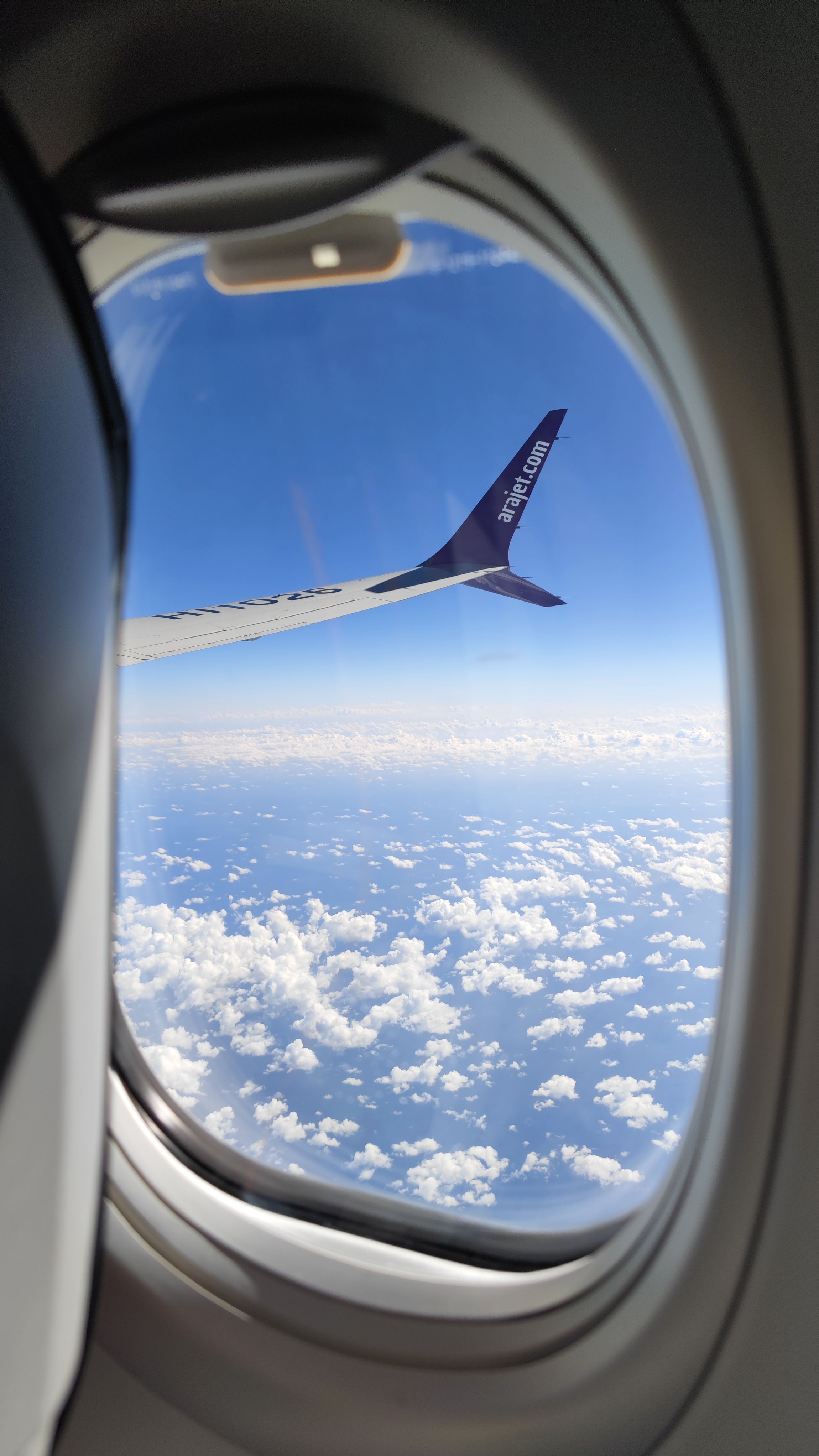 A view of a wingtip of an Arajet Boeing 737 MAX 8 aircraft from a window while in the air