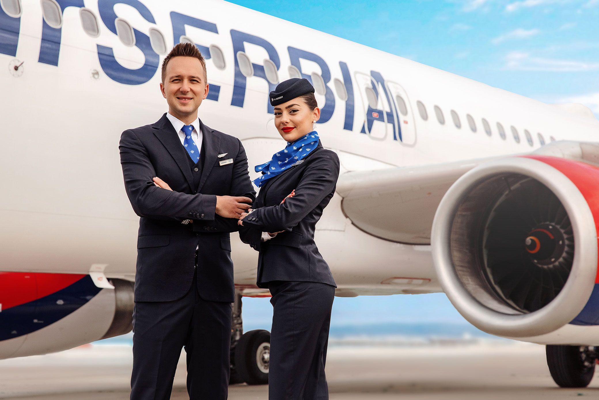 Two Air Serbia cabin crew standing outside an aircraft.