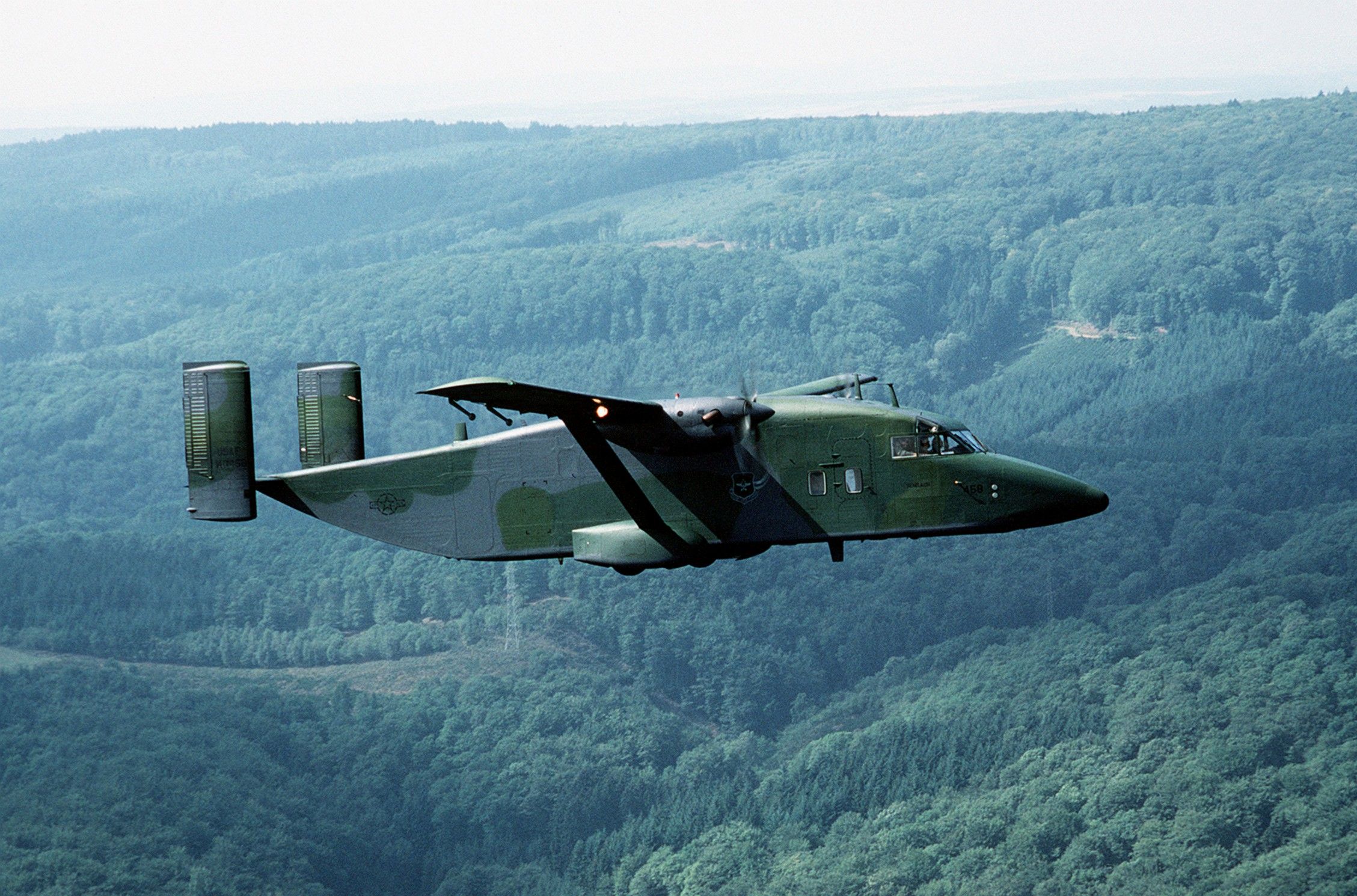 First variant of the Short Sherpa painted in military camouflage colors flying over a wooded area