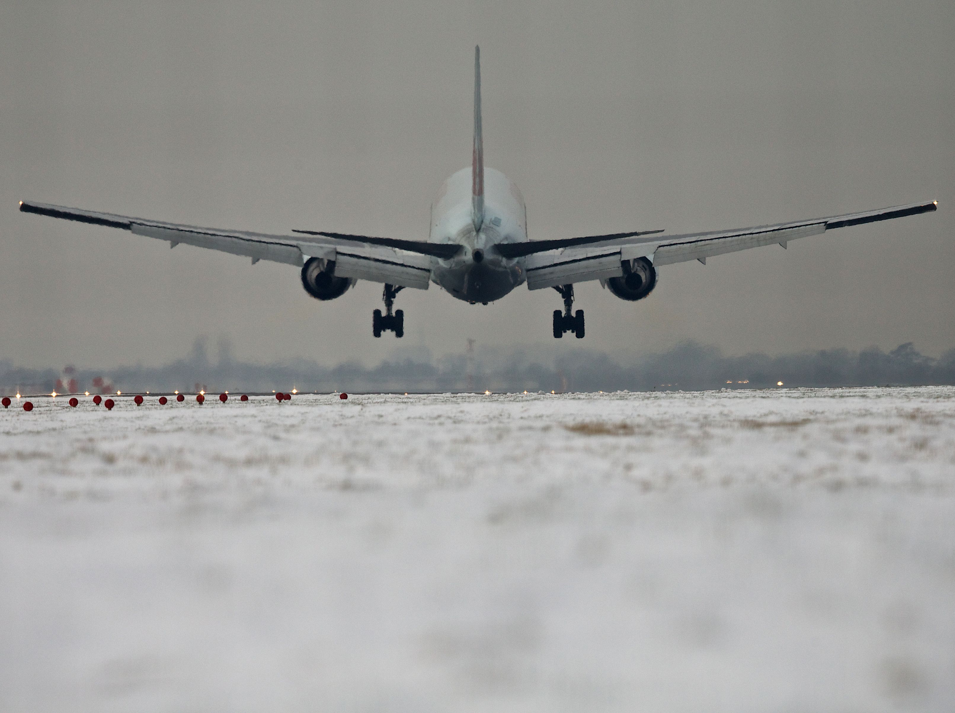 Airplane Silhouette Landing on Snowy Runway 