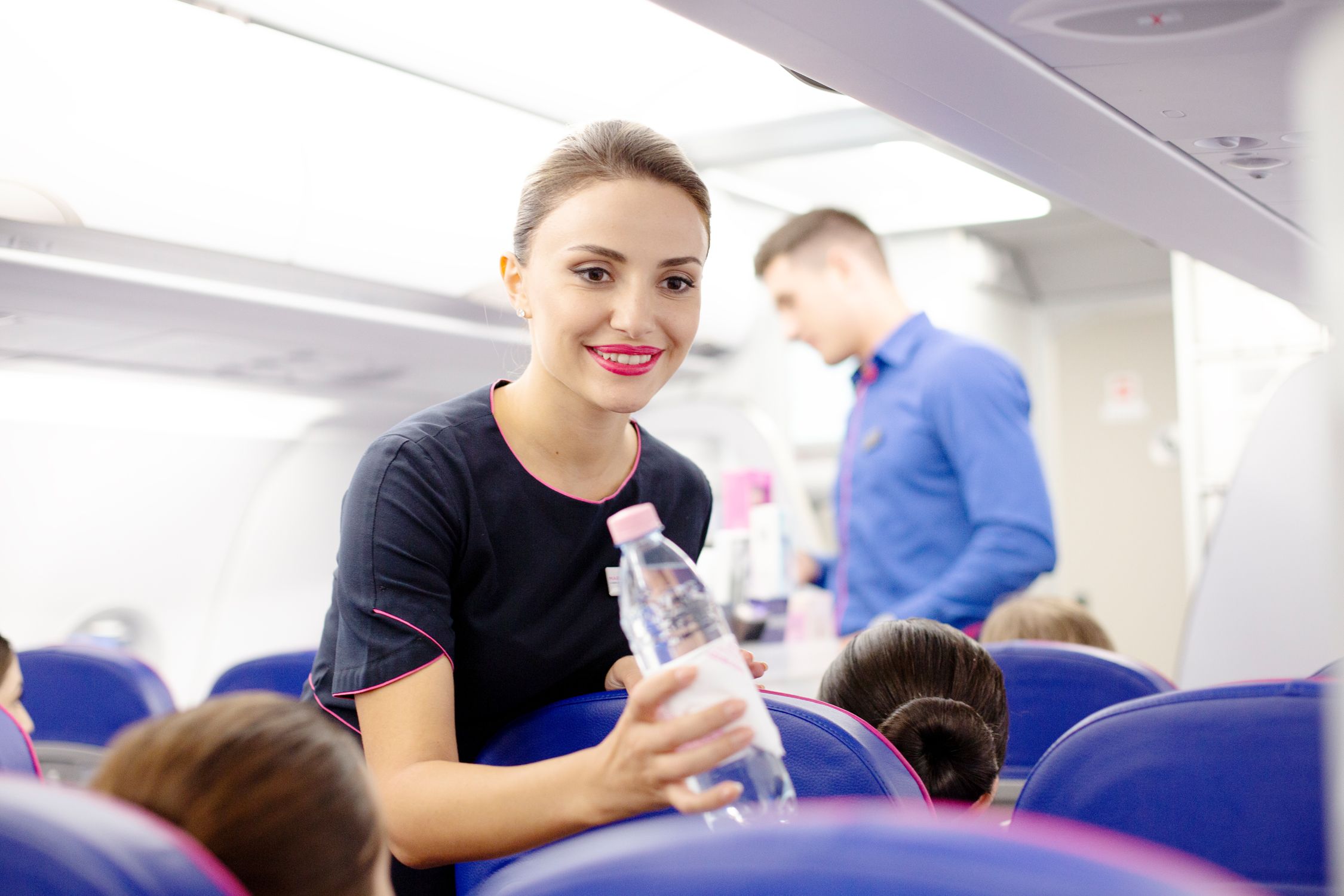 Wizz Air cabin crew giving a passenger a bottle of water.