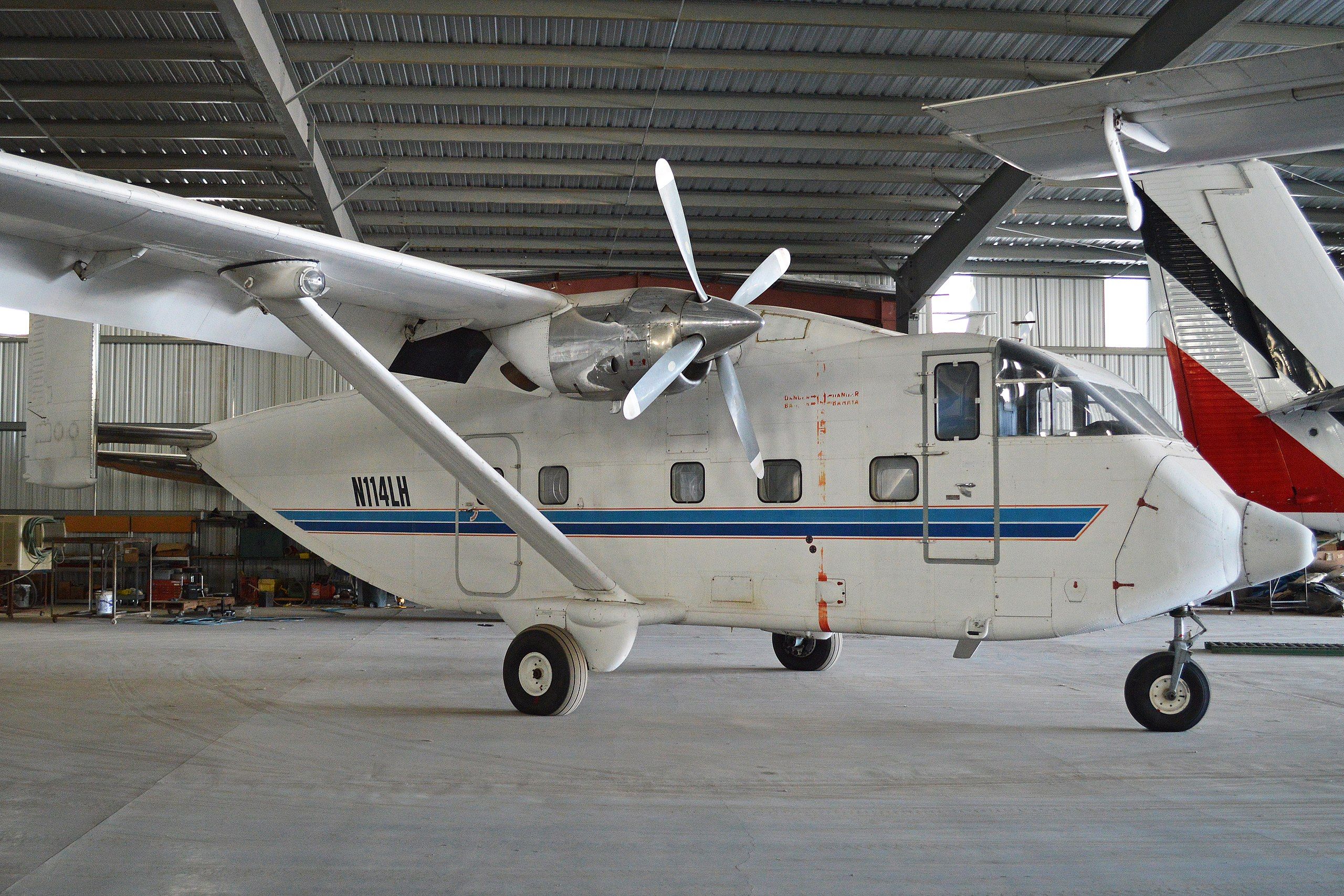A white Short Skyvan with boxy fuselage and high-pointed wings parked in a hangar