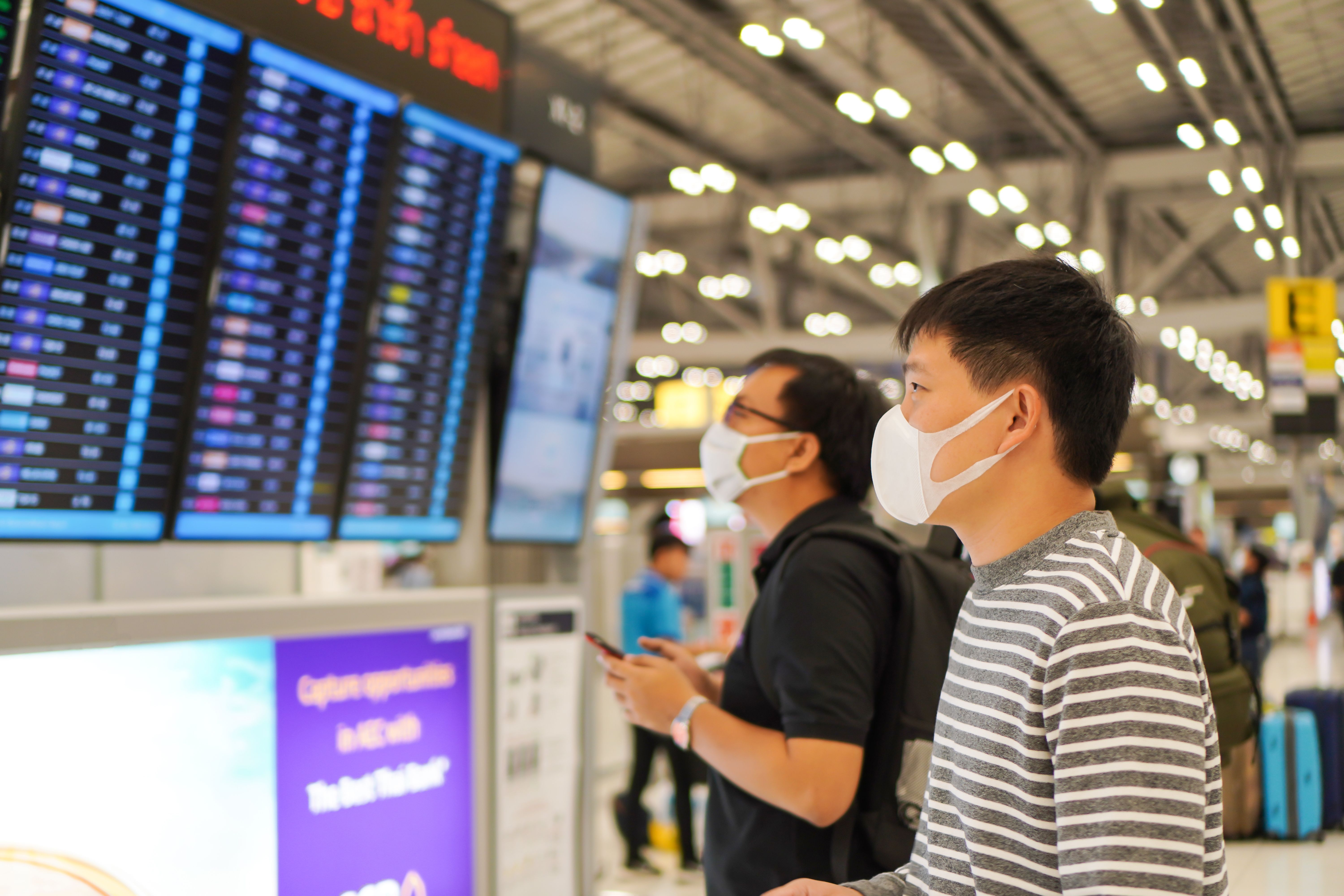 Two Chinese men looking at an airport board
