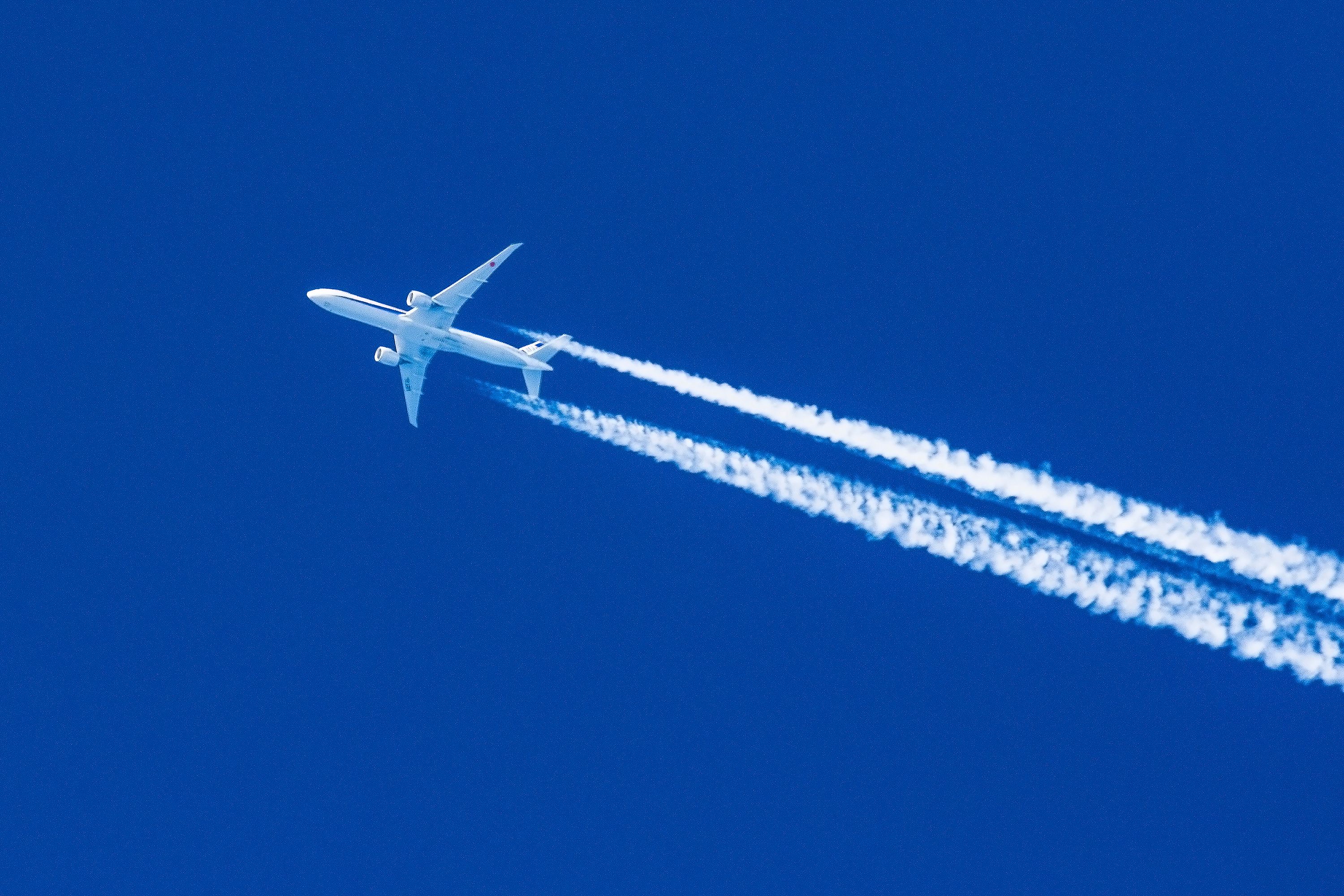 Sharp telephoto close-up of jet plane aircraft with contrails.