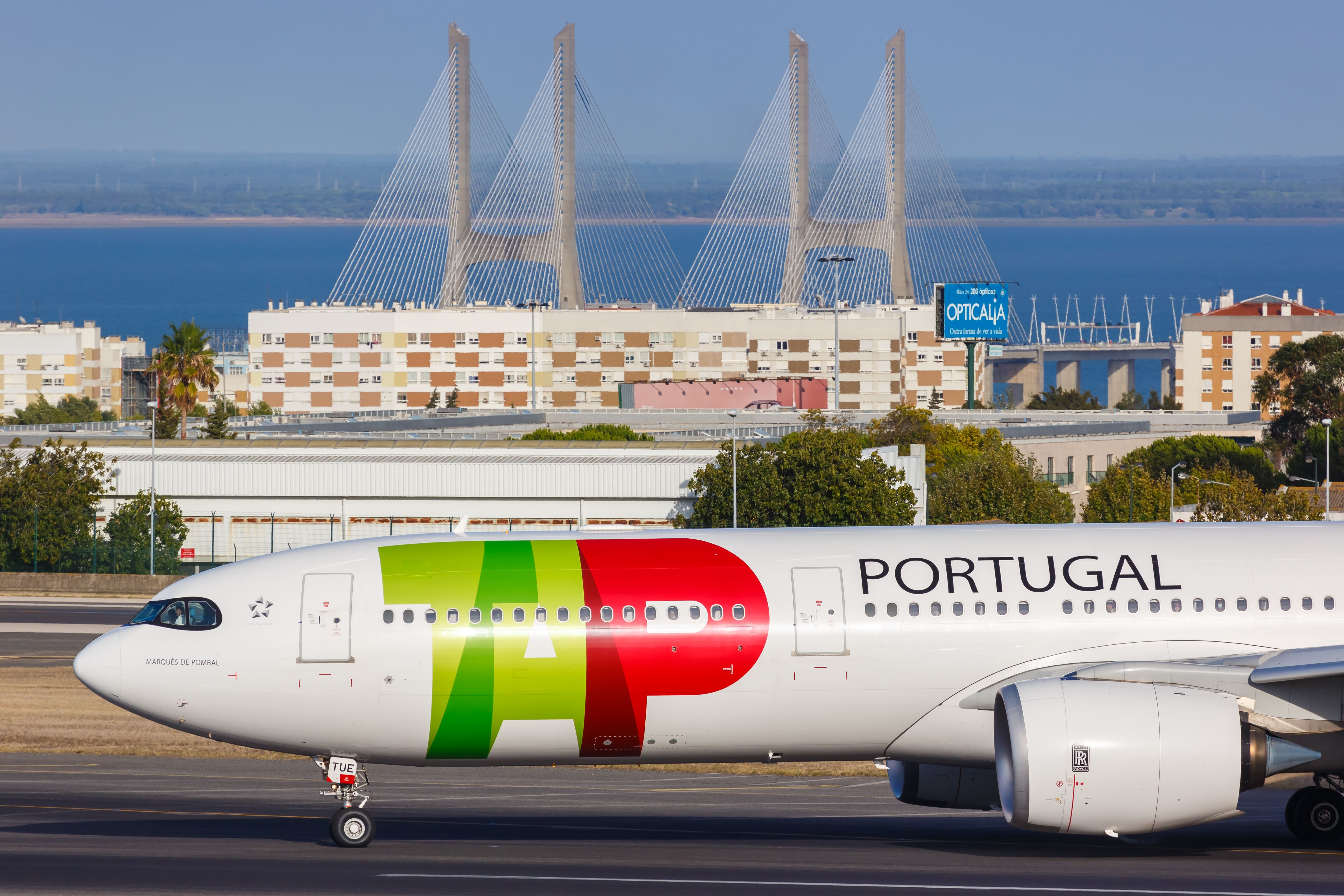 A TAP Air Portugal plane in front of Lisbon's 25 de Abril Bridge