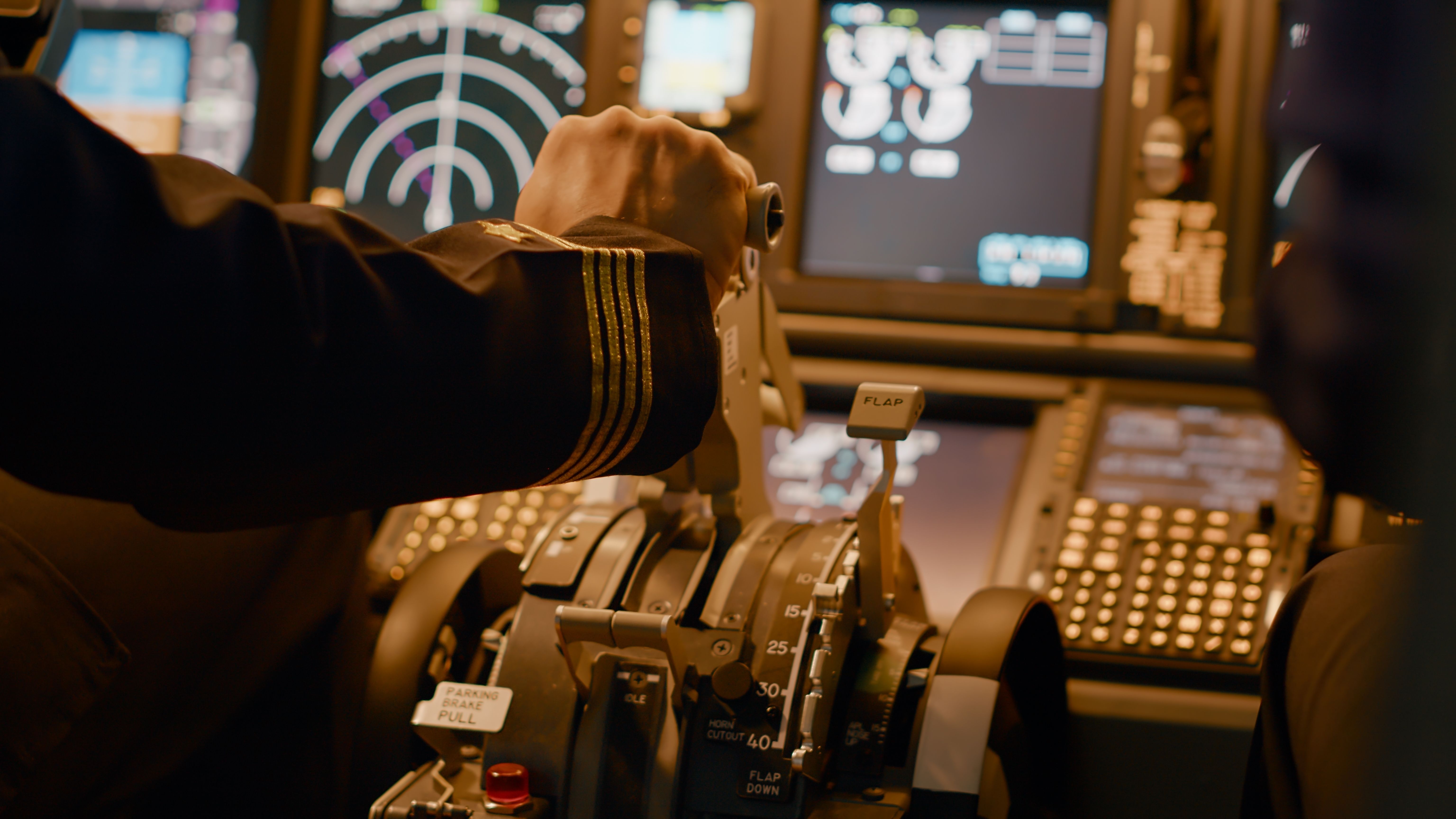 A captain uses the thrust levers in a cockpit. 