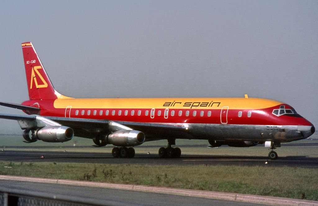 Passenger jetliner shown from the side with red paint on the side and tail, and gold on the top