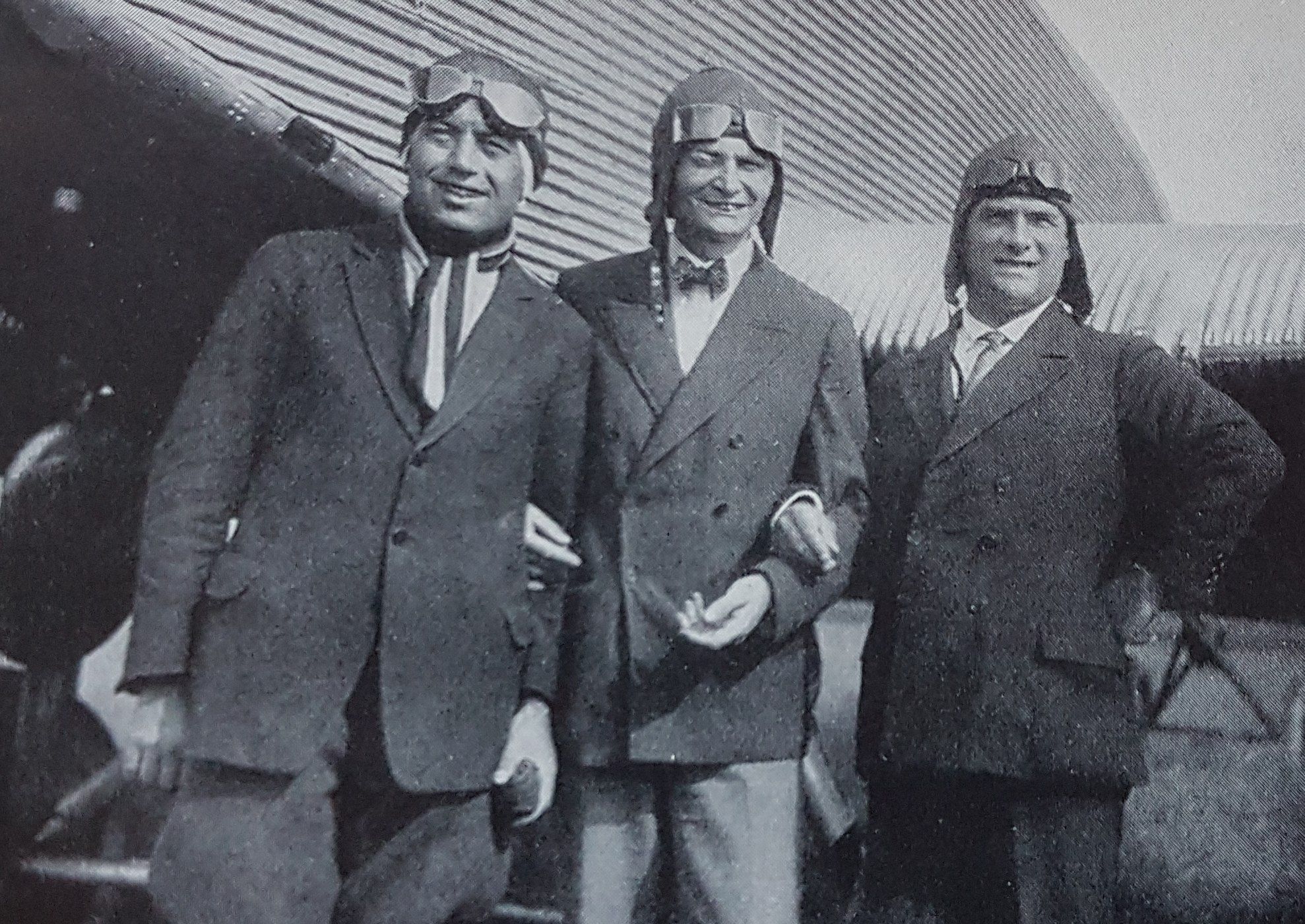 Captain Hermann Koehl, James Fitzmaurice, and Baron von Huenefeld wearing coats and aviator goggles in front of their aircraft