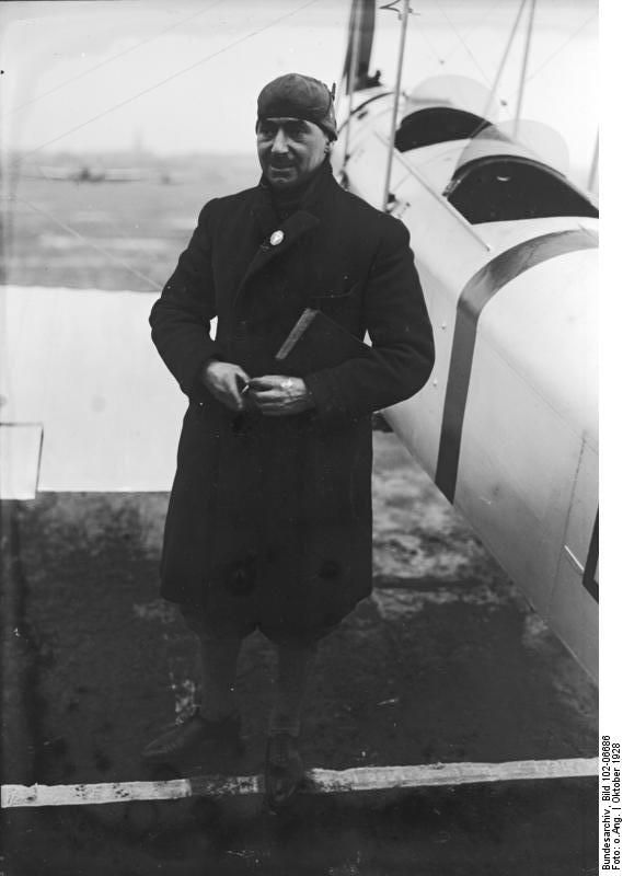 Vintage photo of James Fitzmaurice in a long overcoat and aviator's cap standing next to an aircraft