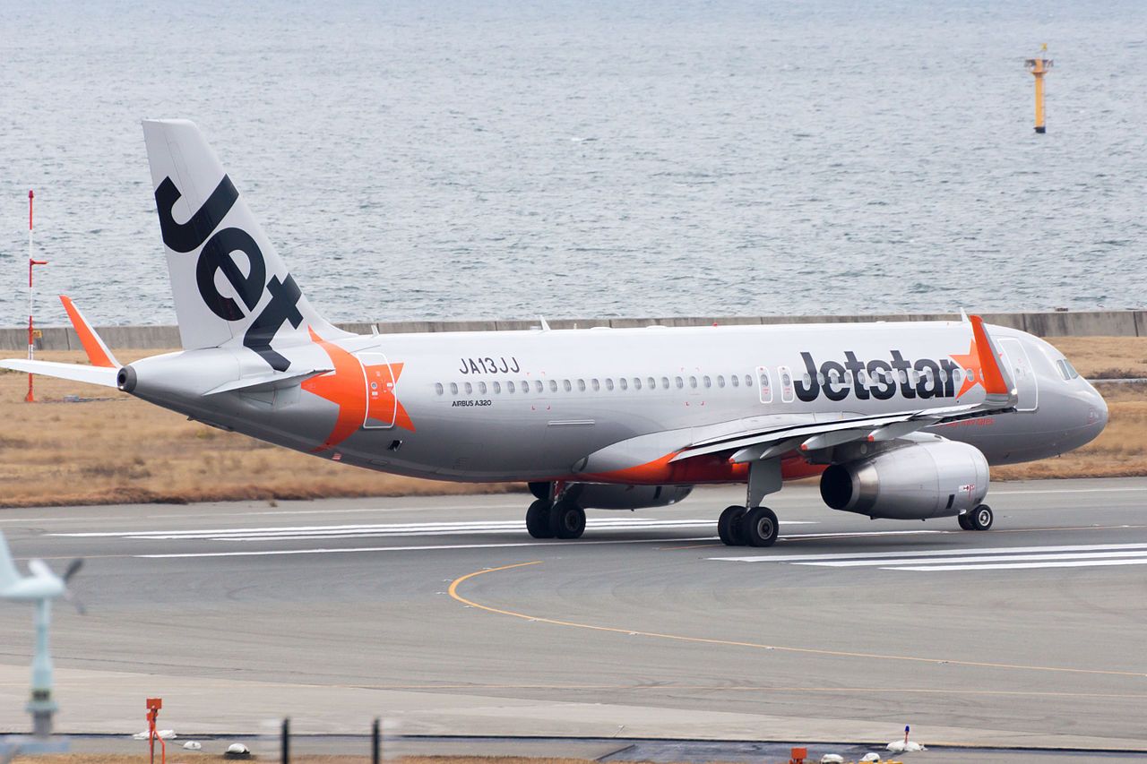 A Jetstar Japan Airubs A320-200 lined up at the end of a runway.