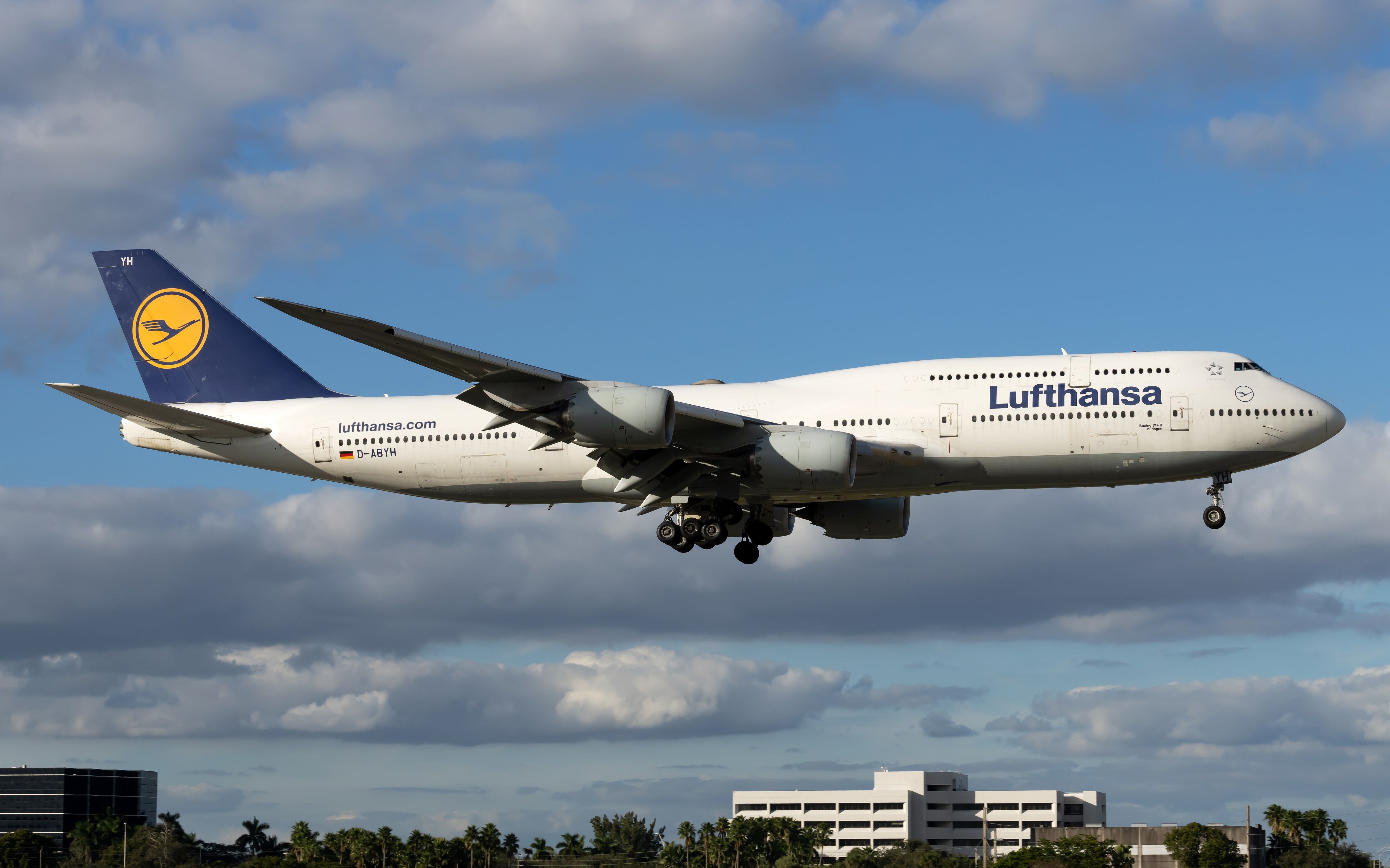 A Lufthansa Boeing 747-8 flying low to the ground.