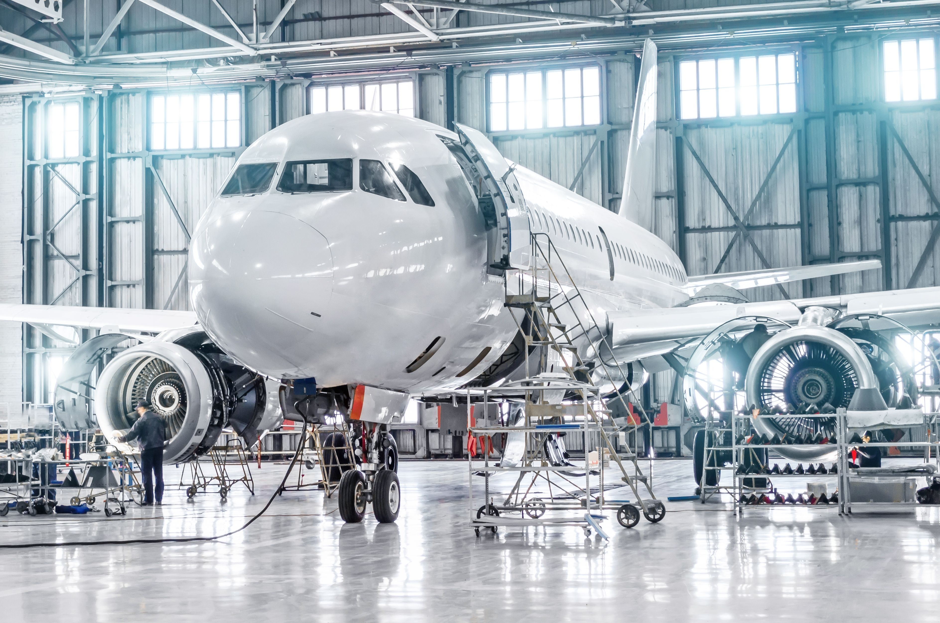 A Passenger aircraft in an airport hangar for maintenance of its engines and fuselage.