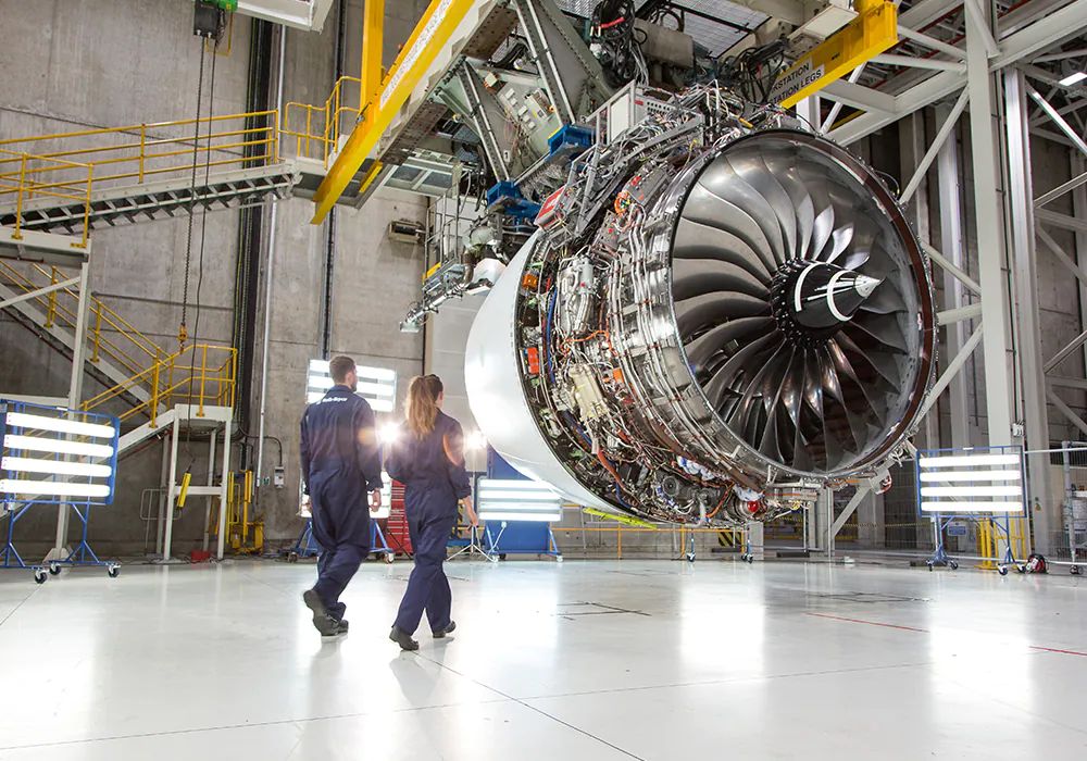 Two Rolls-Royce engineers standing near a Trent XWB engine.