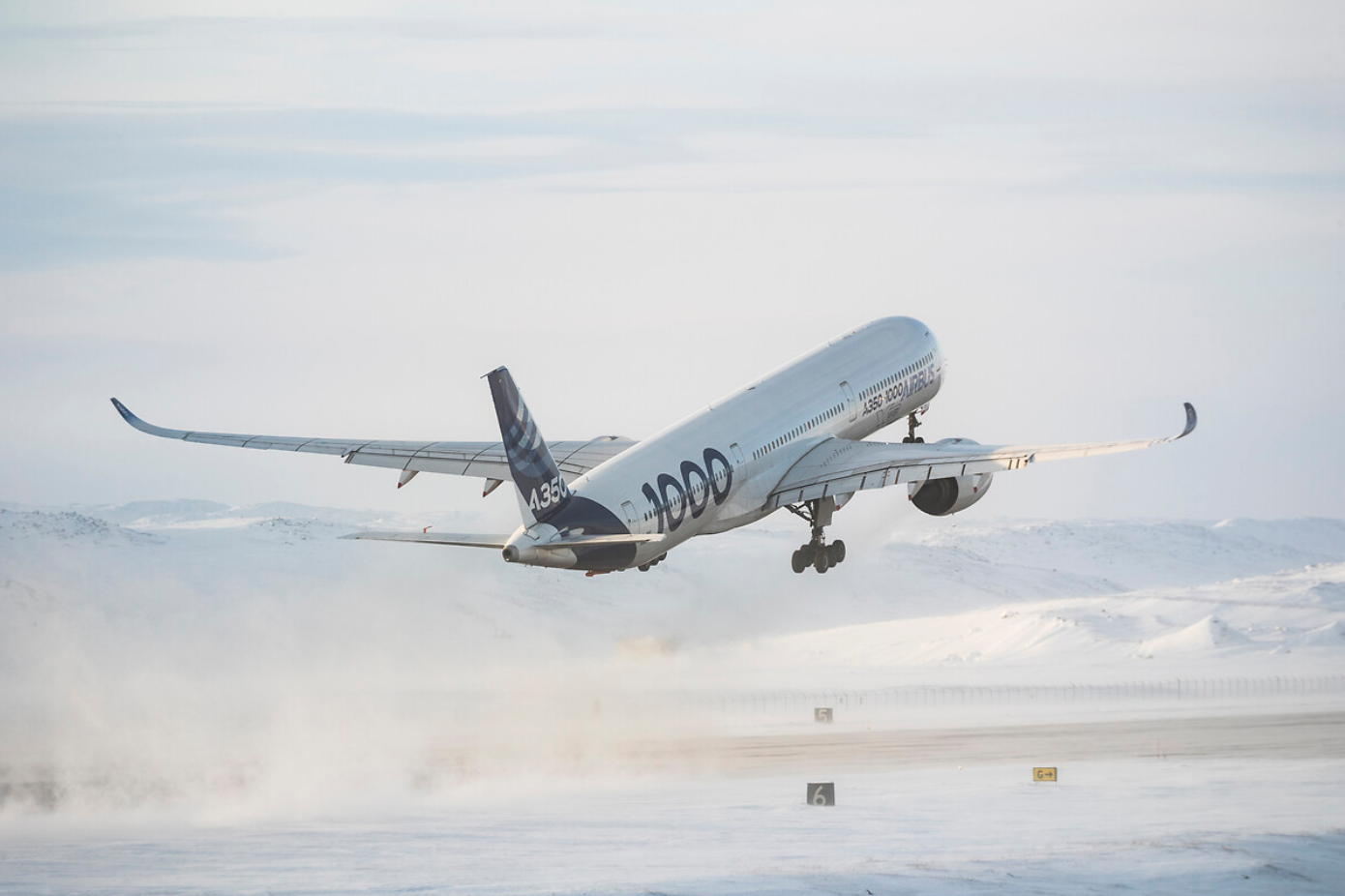 An Airbus A350 takes off in snowy conditions.