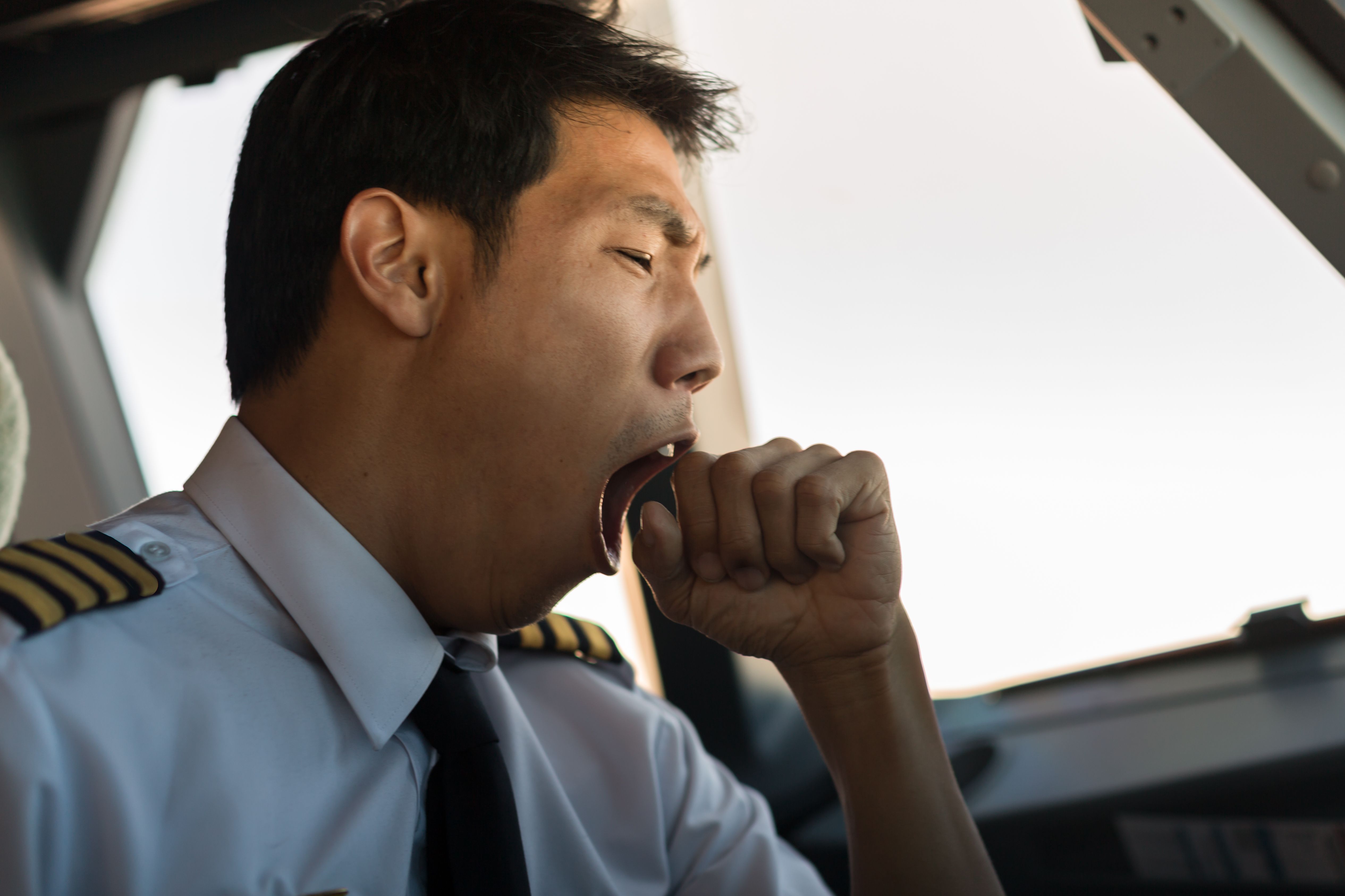 A pilot yawning in the cockpit