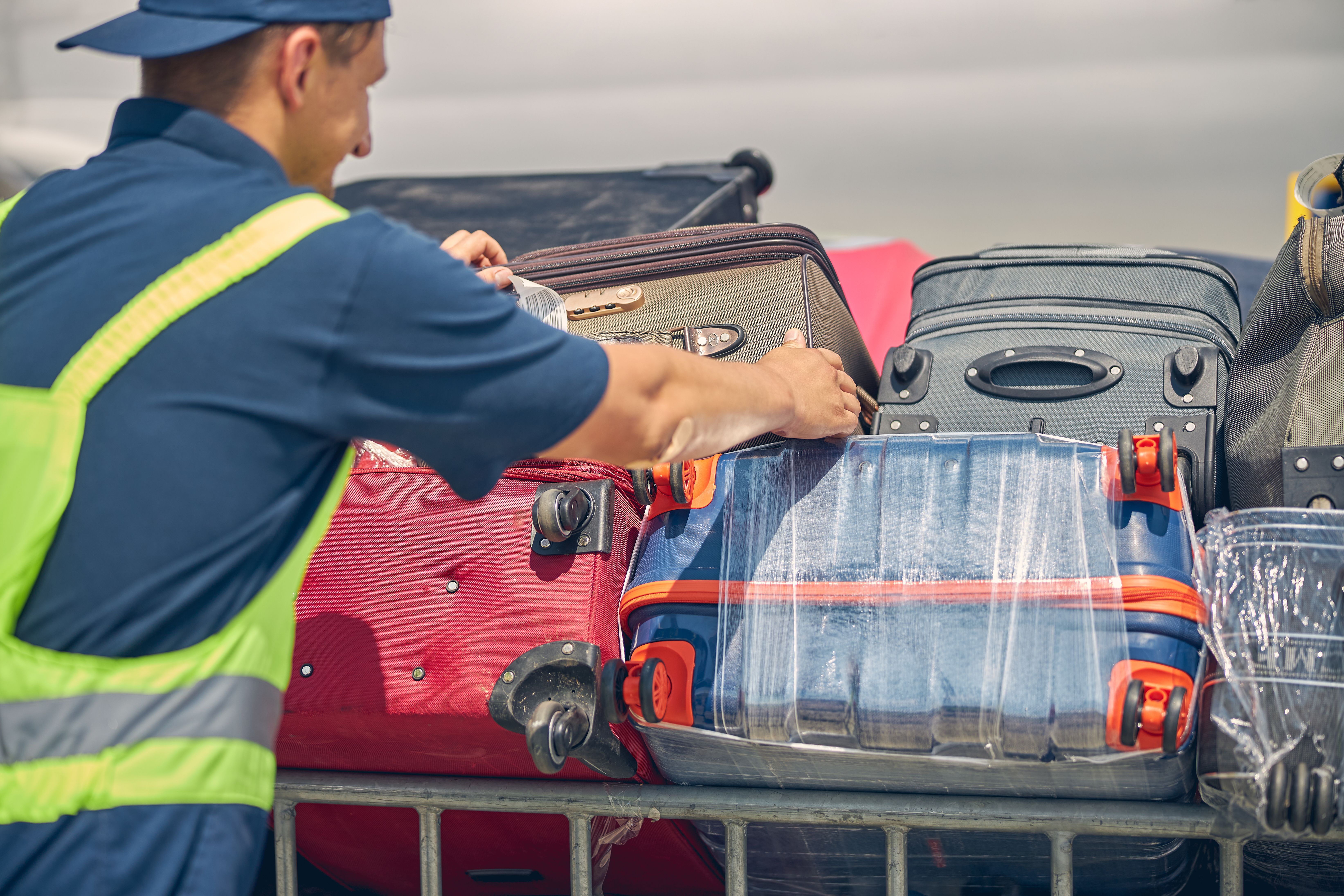 A Baggage handler moving luggage cases.