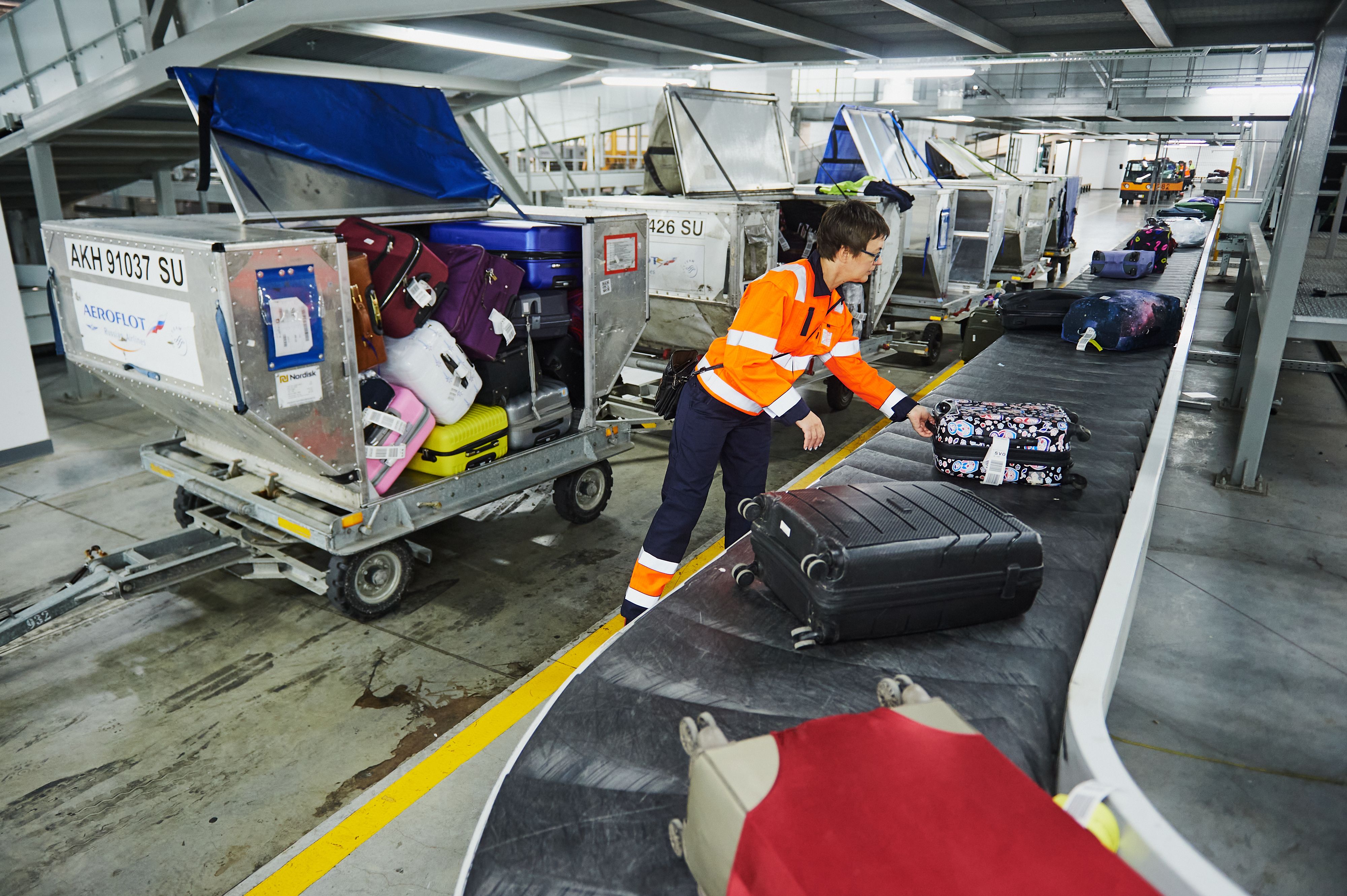 A baggage handler filling up a cargo container with bags. 