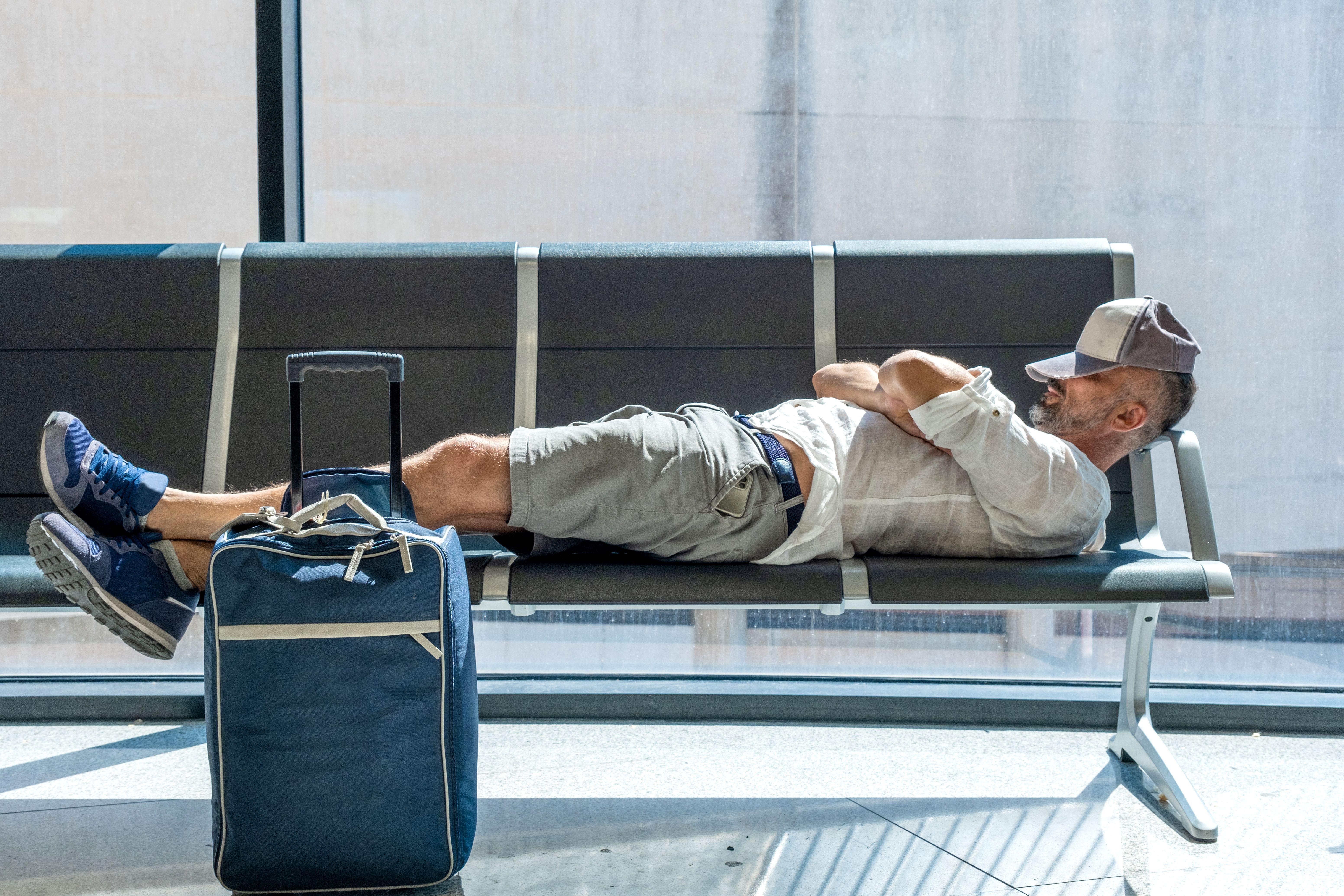 Man sleeping on airport gate seats.