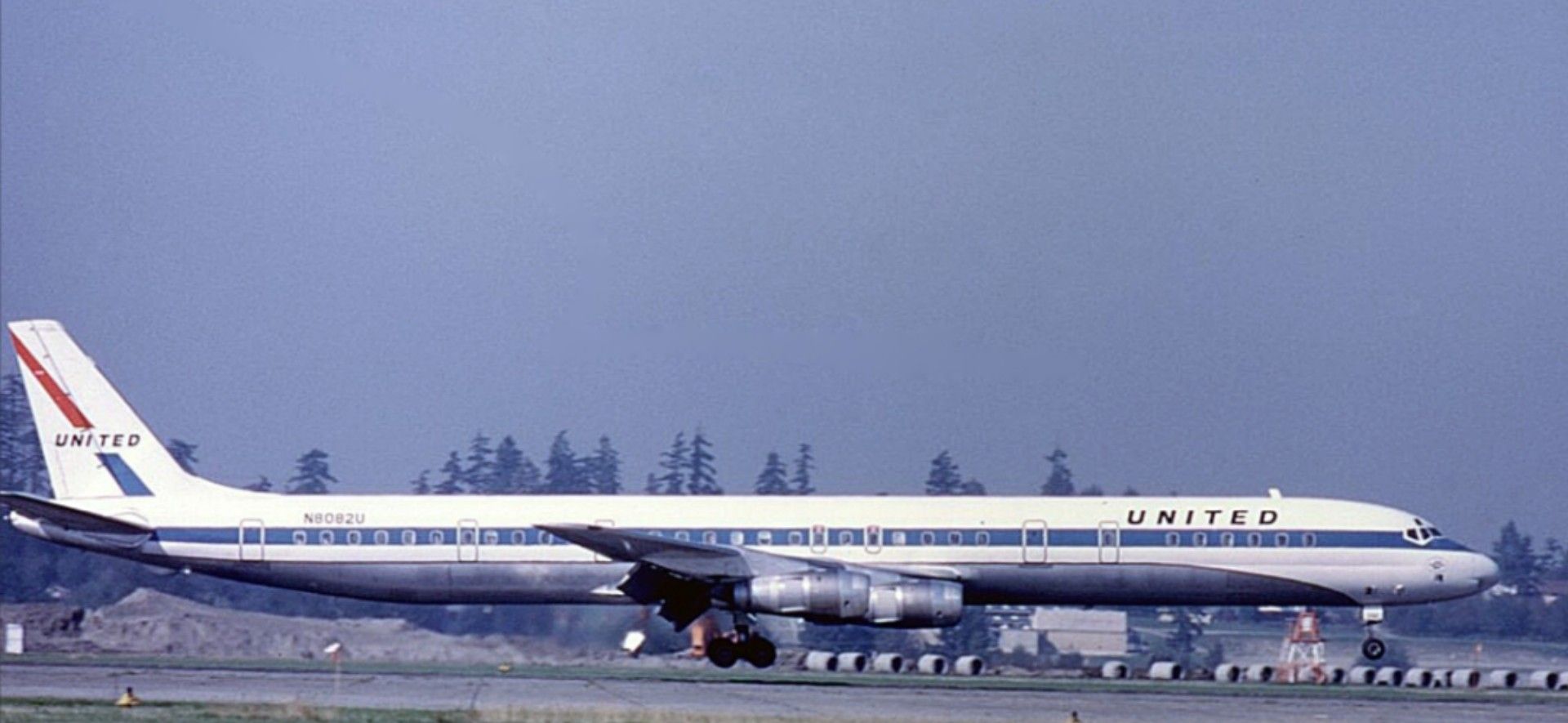 White passenger jetliner with navy blue stripe down the side and United branding near the nose and on the tail