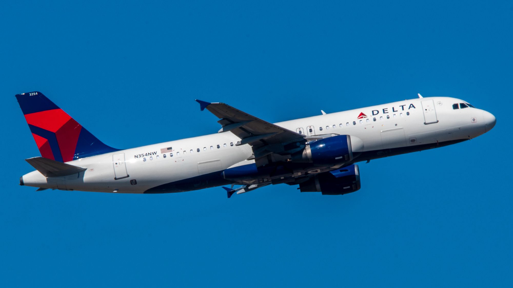 White jetliner with Delta Airlines logo on side and tail ascending in blue sky