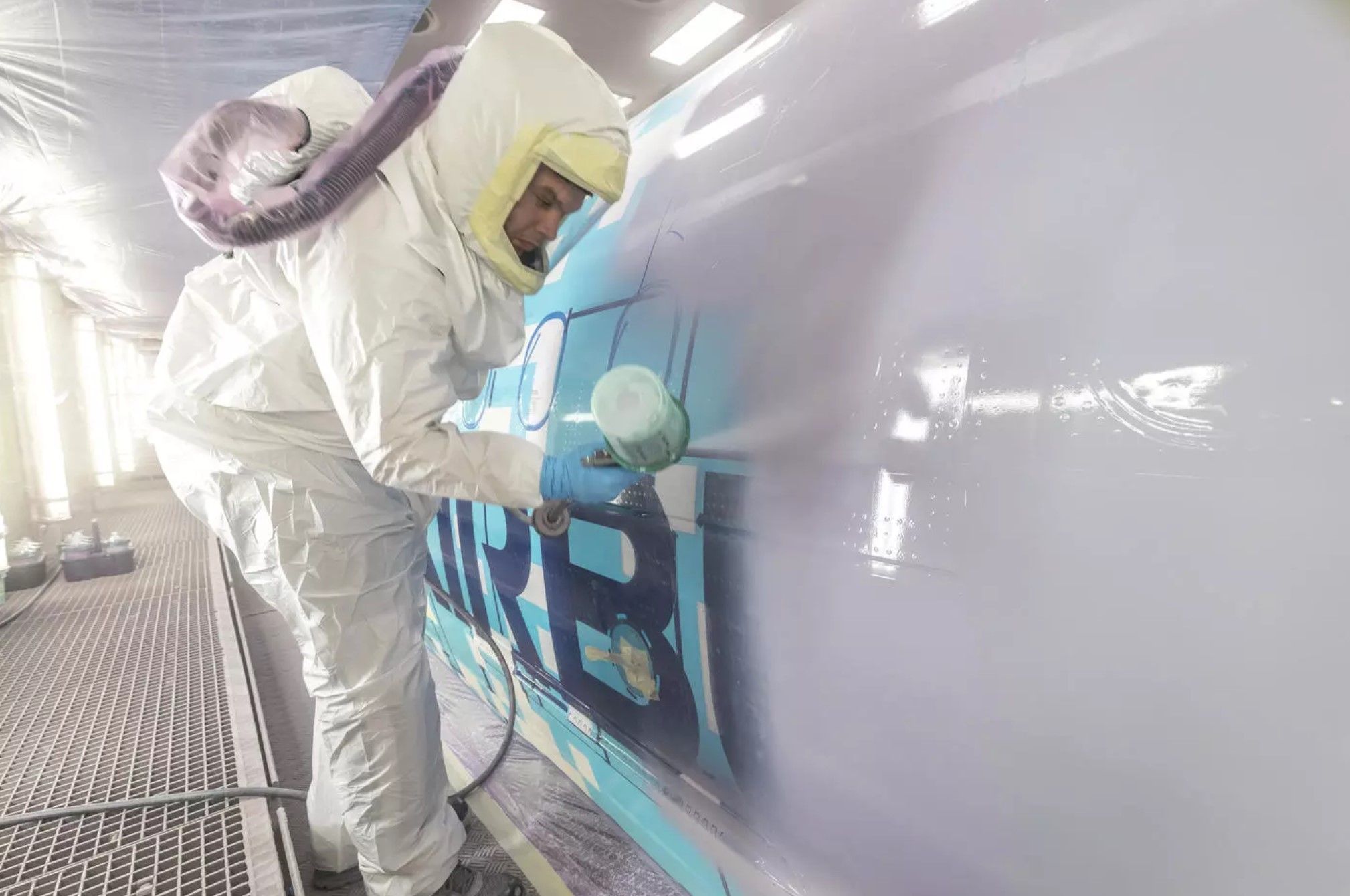 A worker in a coverall spraypaints the Airbus A321XLR.