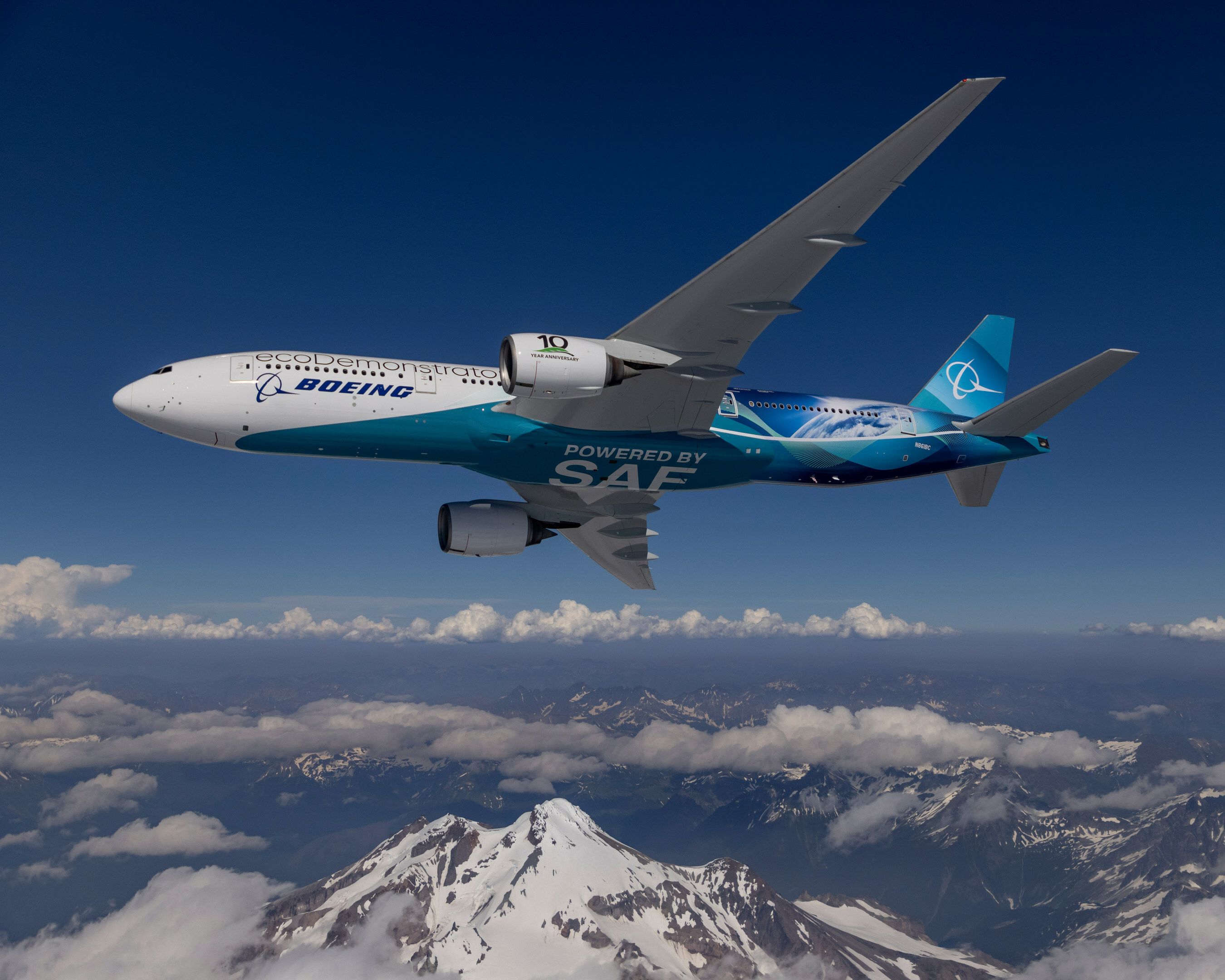 Boeing ecodemonstrator plane with SAF logo in the sky over mountains