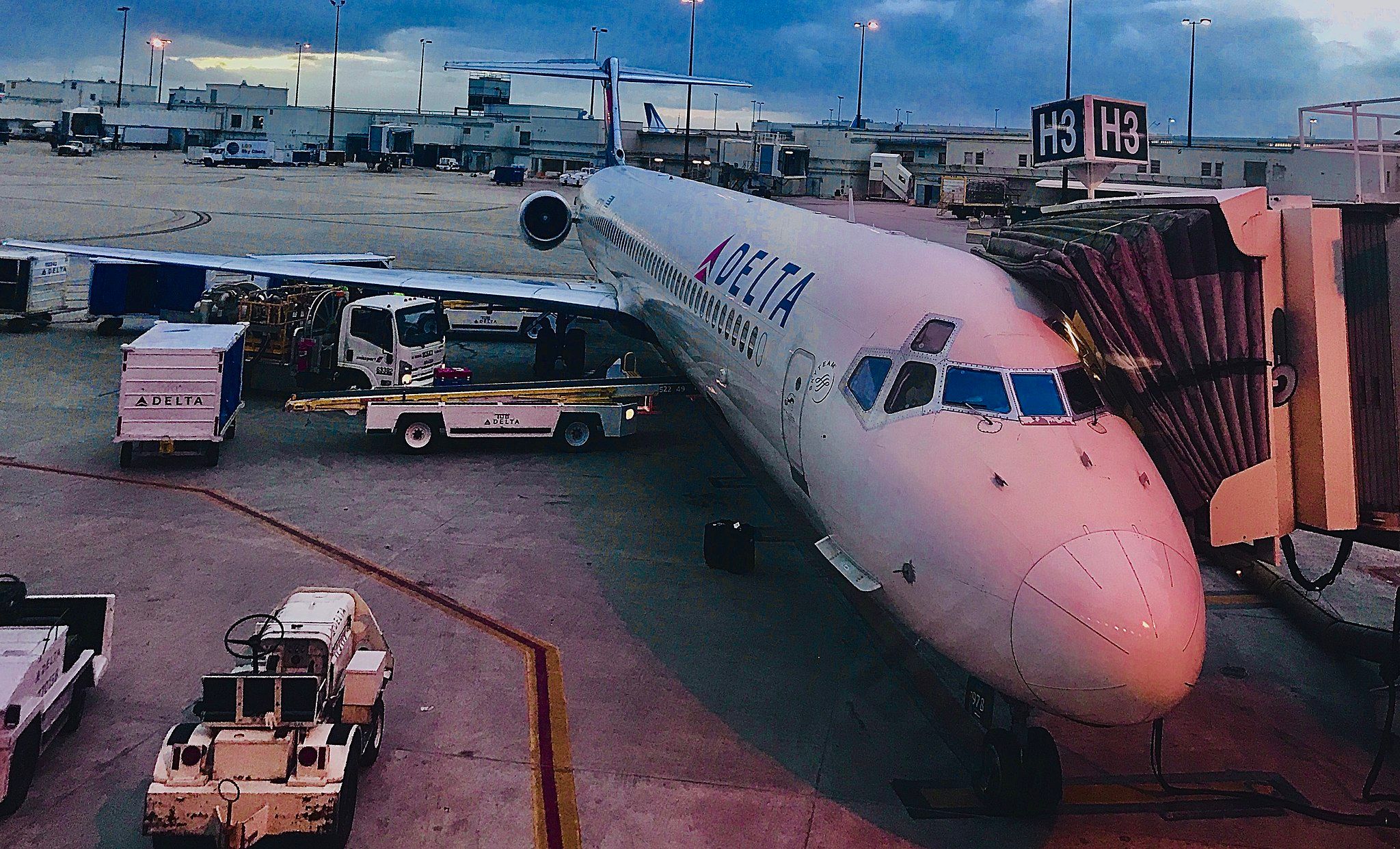 A white Delta Airlines jetliner parked at the gate connected to jet bridge