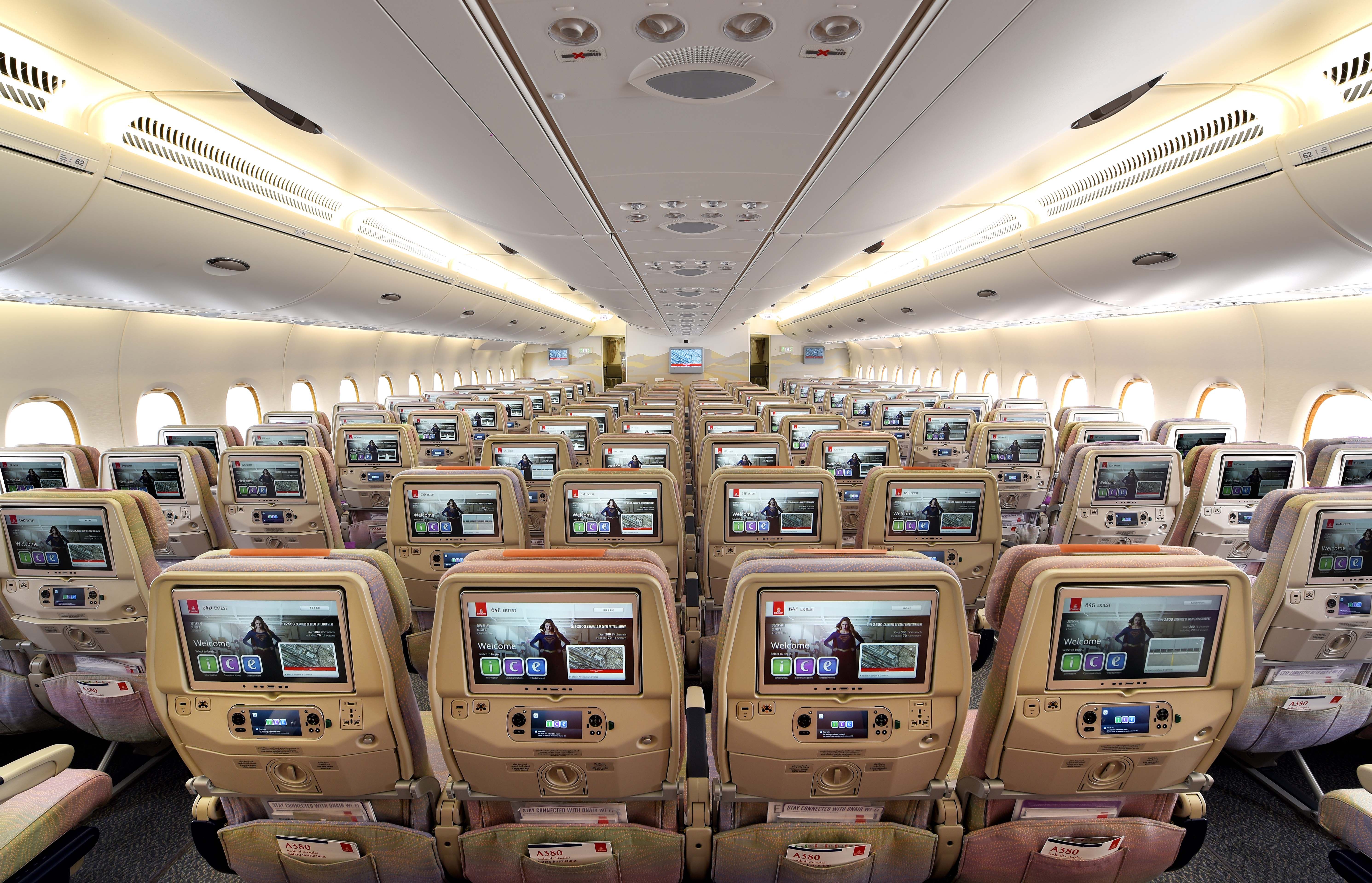 Wide shot of Emirates Economy cabin. All entertainment screens in the seats are in full view.