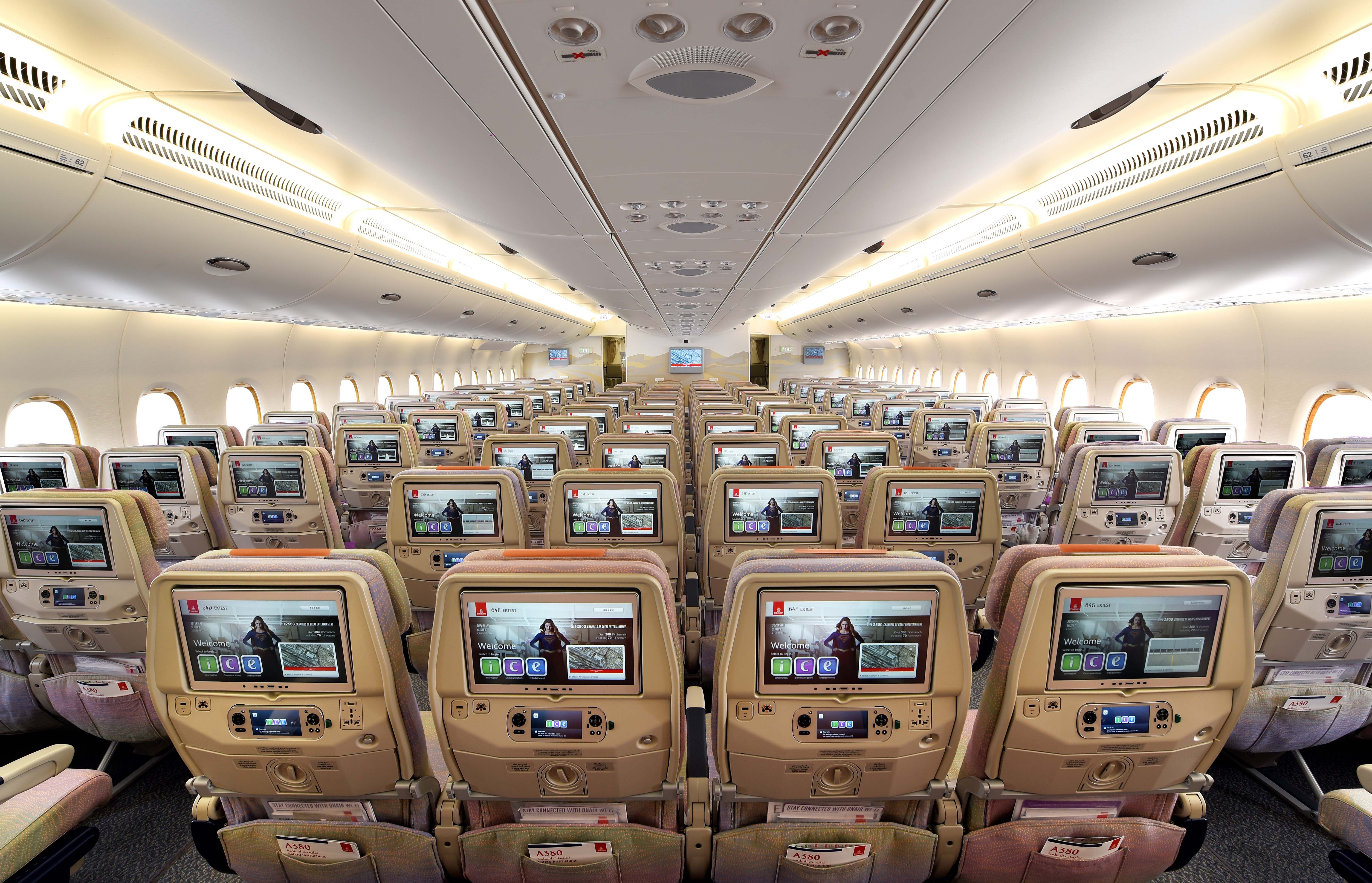 A Wide shot of the Emirates economy cabin, with all seat-back entertainment screens in full view.