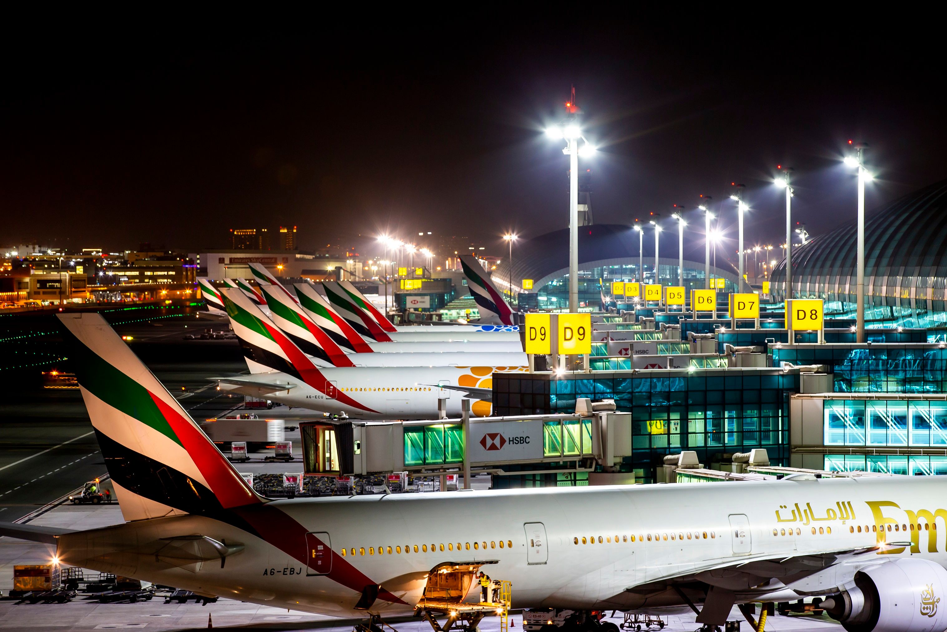 Many Emirates aircraft parked at gates at Dubai International Airport.