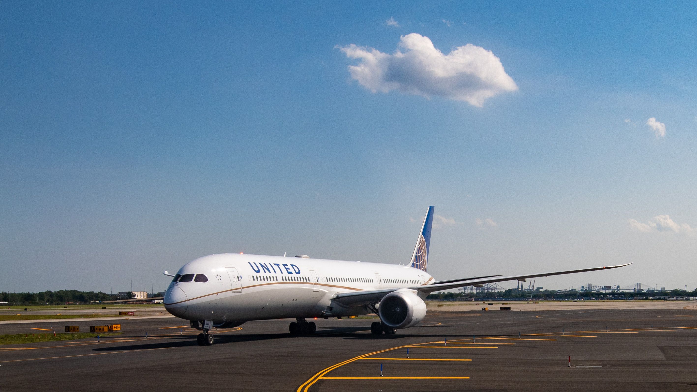White Boeing 787 jetliner with United in blue lettering on the side sitting on taxiway