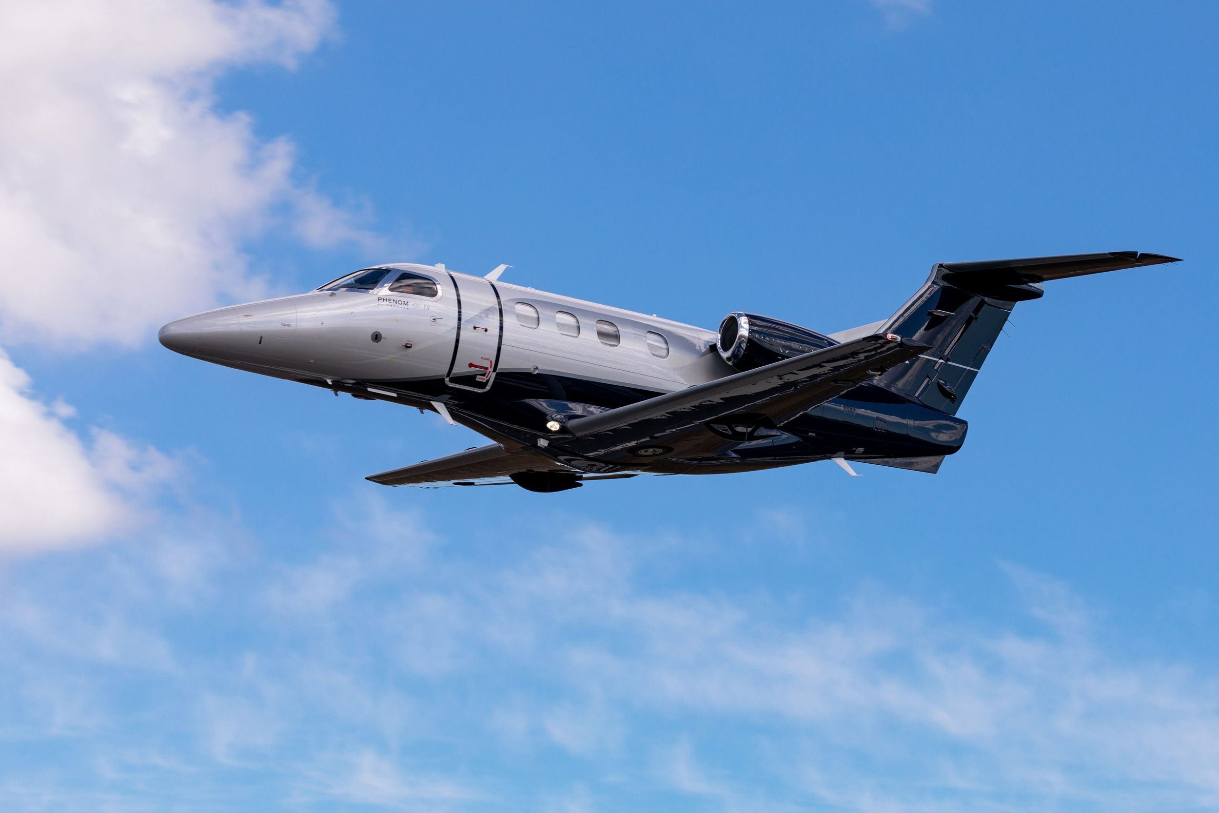 An Embraer Phenom 100EV business jet flying in the sky.